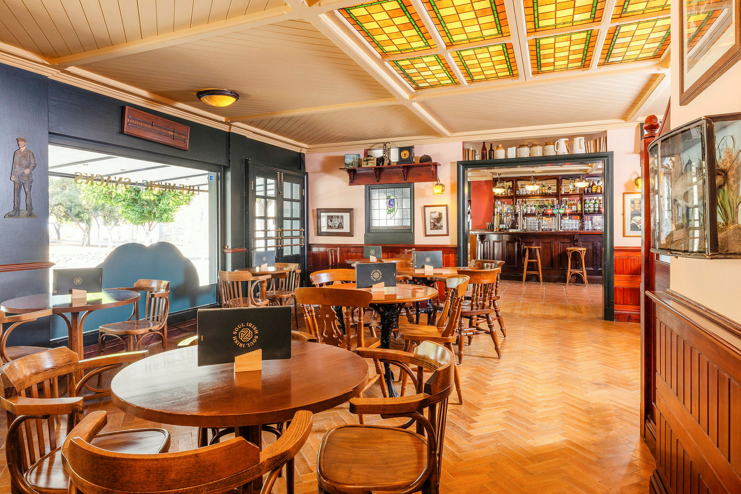 Interiør af en pub med træstole og borde samt en bar i baggrunden. (AI-genereret tekst)