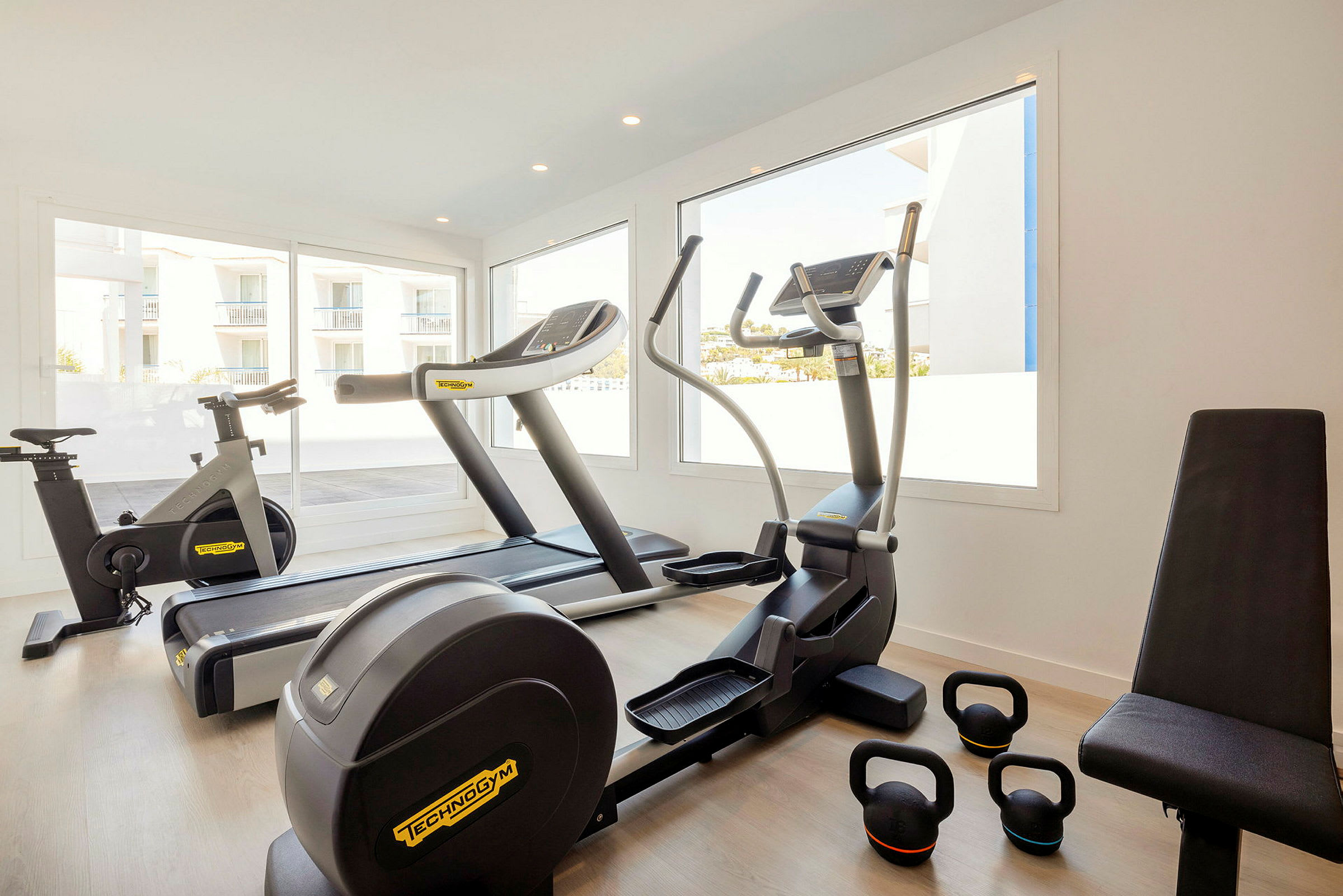 Et fitnesscenter med træningsudstyr såsom cykel, løbebånd, crosstrainer og kettlebells. (AI-genereret tekst)