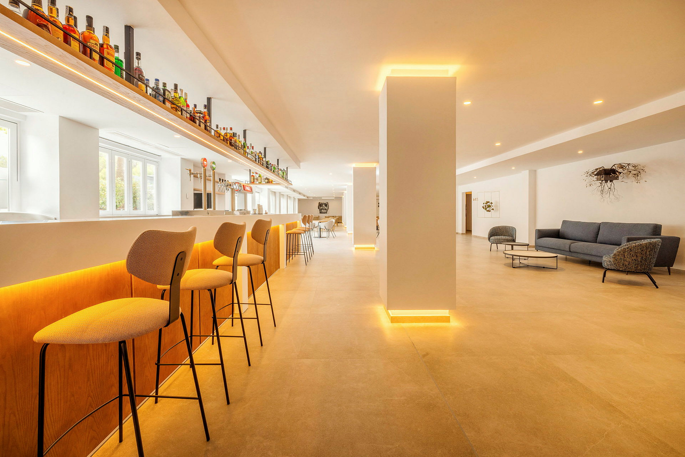 En moderne bar med høje stole, lys indretning og et loungeområde med sofaer og borde. (AI-genereret tekst)