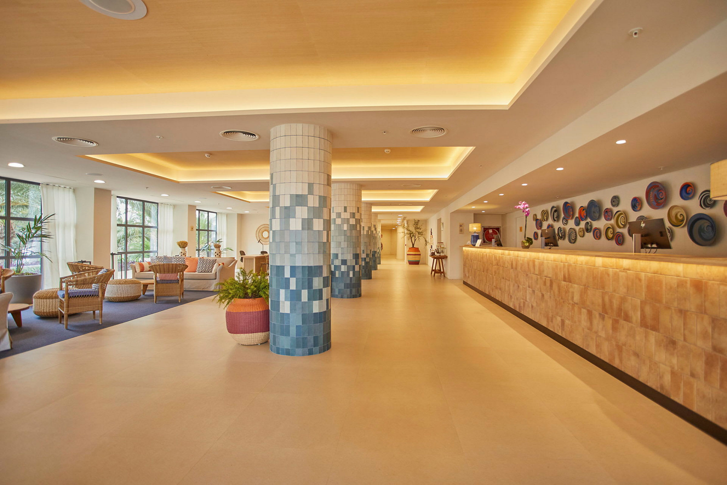 Hotellobby med siddeområder, dekorerede søjler og reception. (AI-genereret tekst)