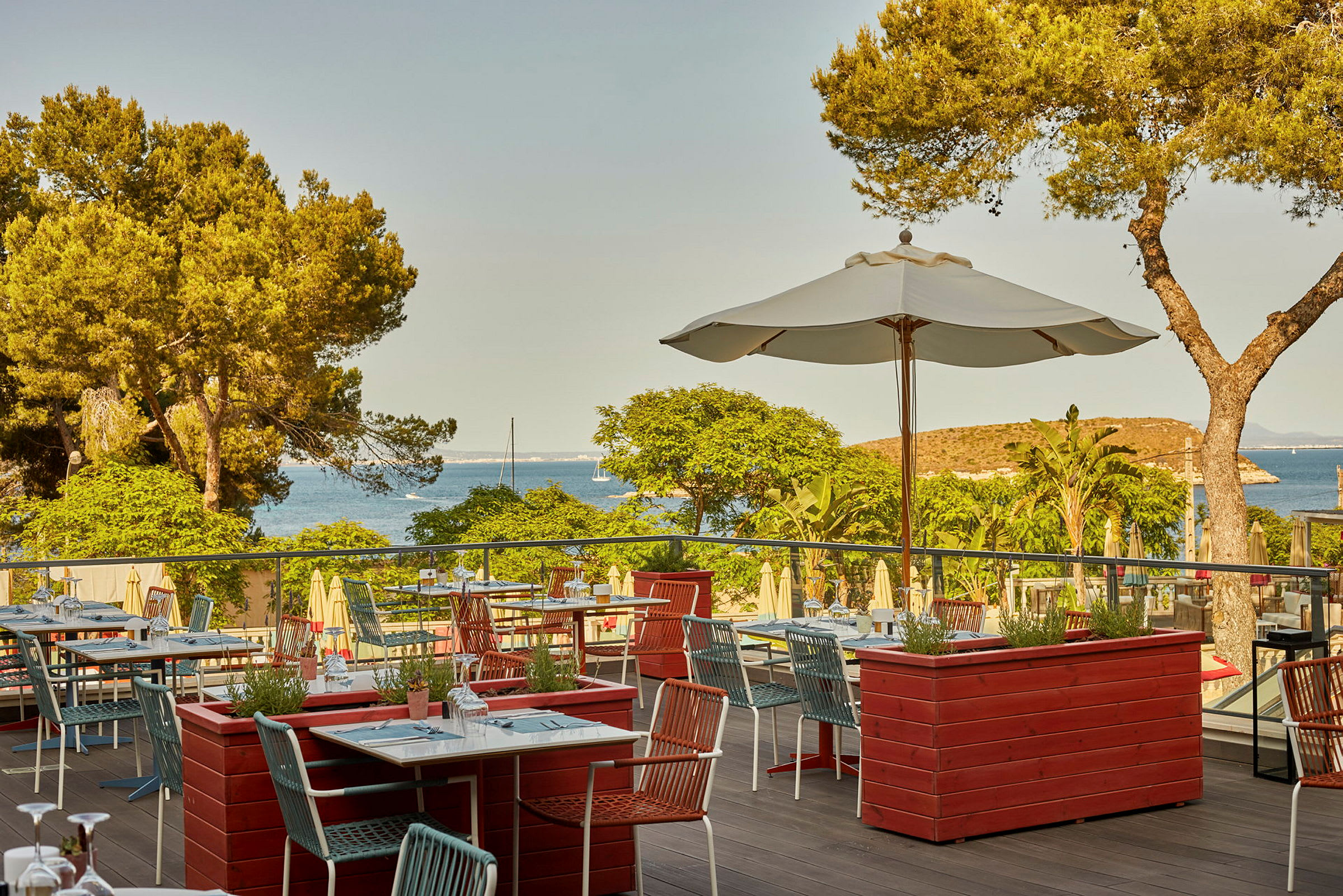 En terrasse restaurant med udsigt over havet og fyrretræsskov. (AI-genereret tekst)