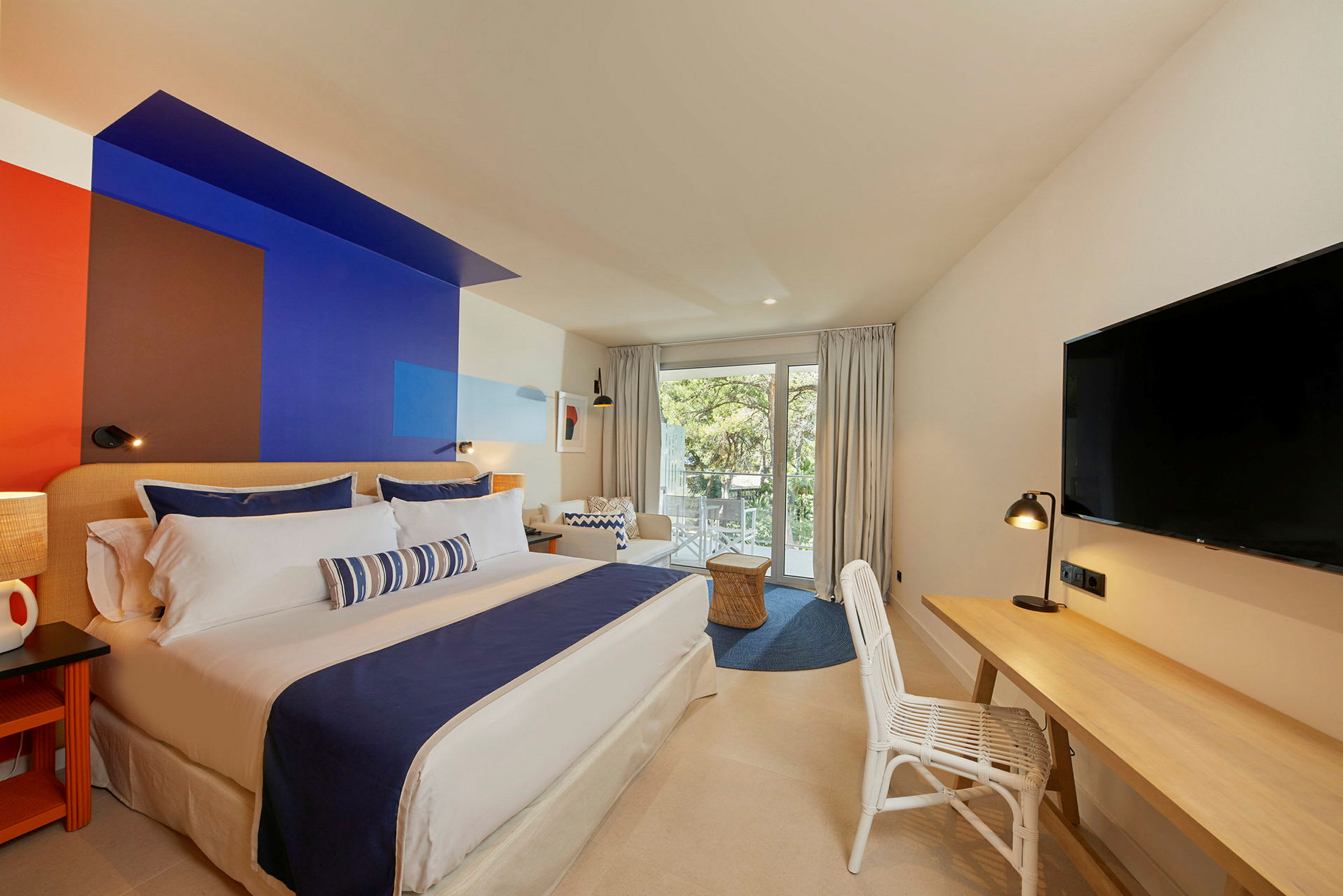 Moderne hotelværelse med en stor dobbeltseng og et farverigt vægdesign. (AI-genereret tekst)
