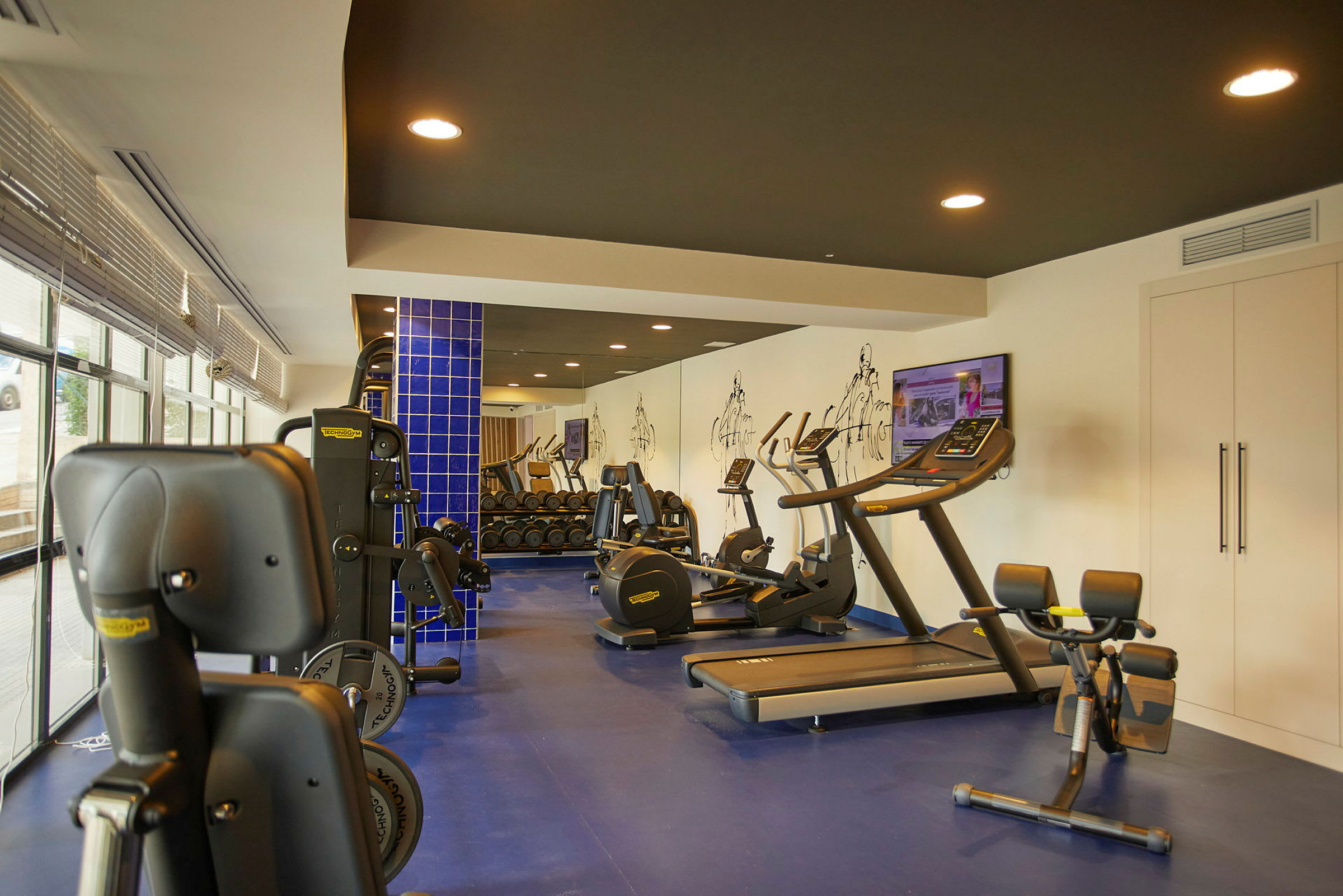 Billede af et fitnesscenter med træningsmaskiner og vægte. (AI-genereret tekst)