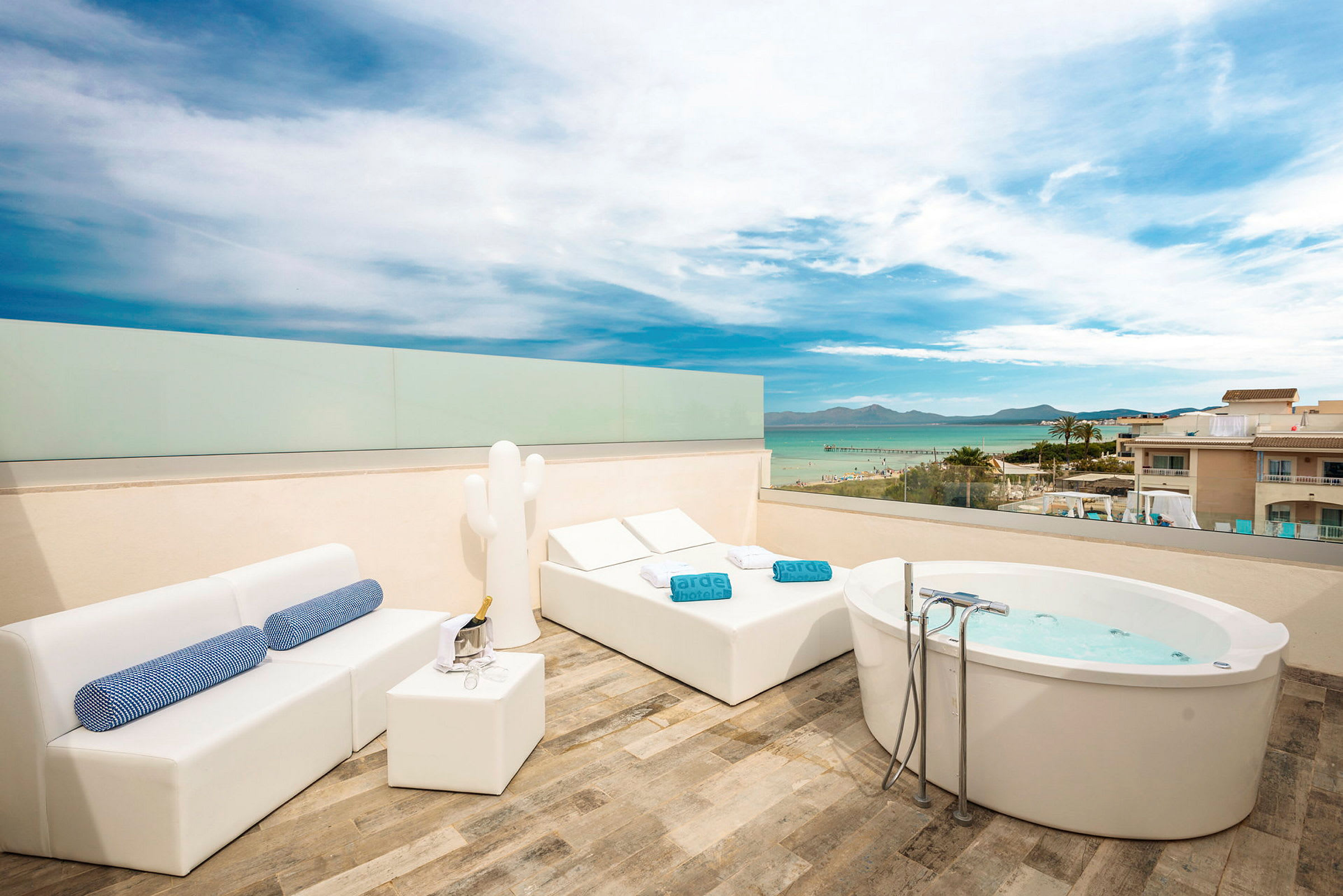 Tagterrasse med havudsigt, udstyret med jacuzzi, liggestole og sofamiljø. (AI-genereret tekst)