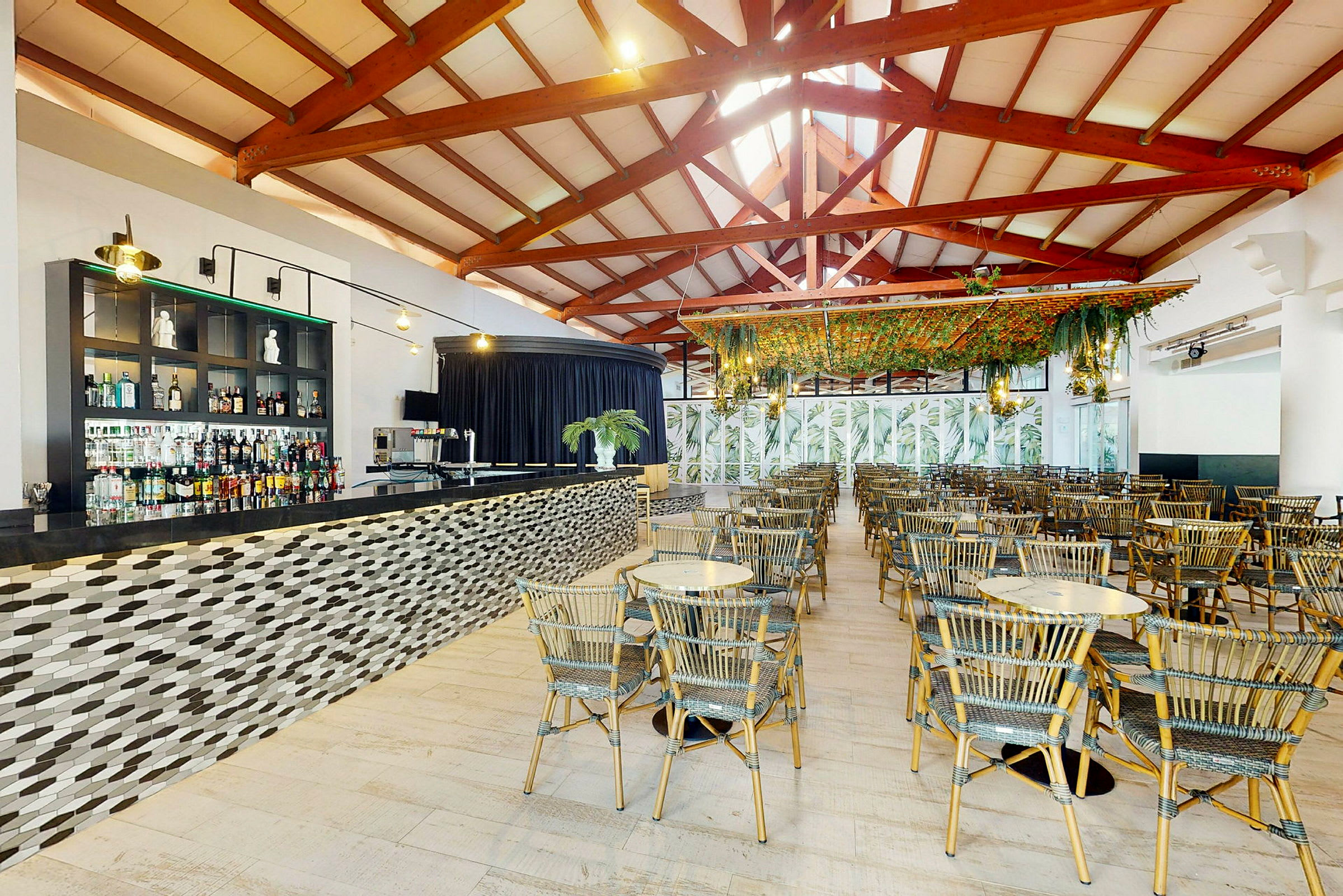 En stor restaurant med en bar, mange stole og borde. (AI-genereret tekst)
