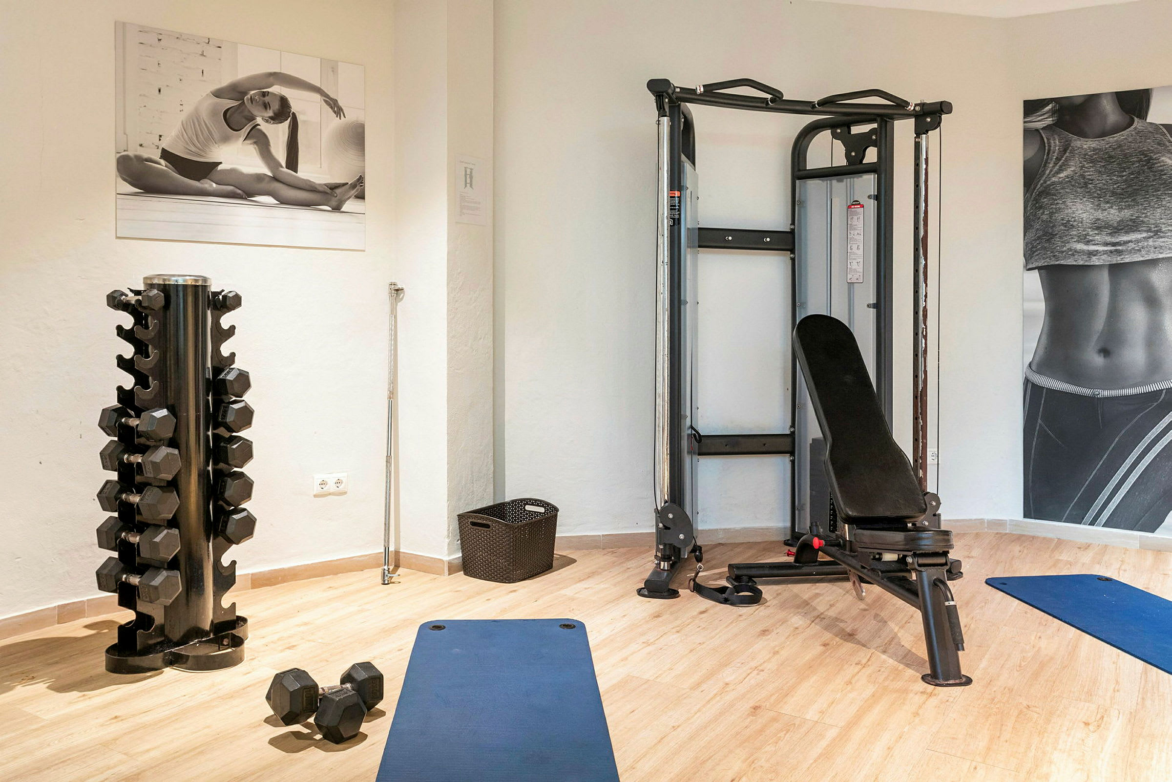 Et fitnessrum med håndvægte, træningsmaskiner og en blå yogamåtte. (AI-genereret tekst)