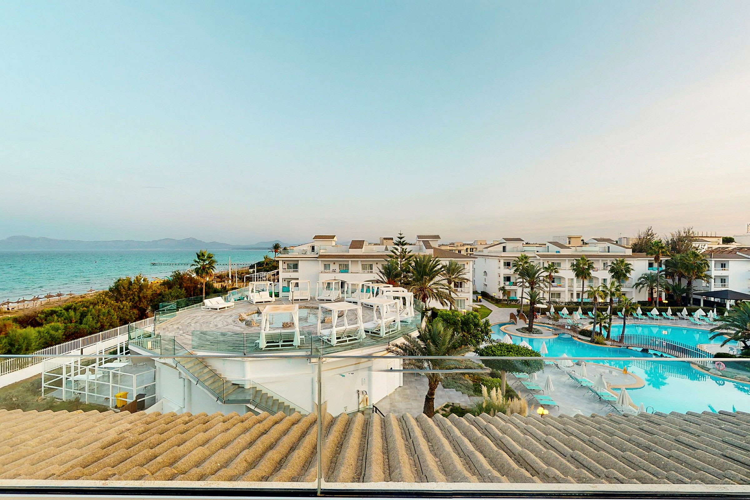 Hotelområde med pool og strand i baggrunden. (AI-genereret tekst)