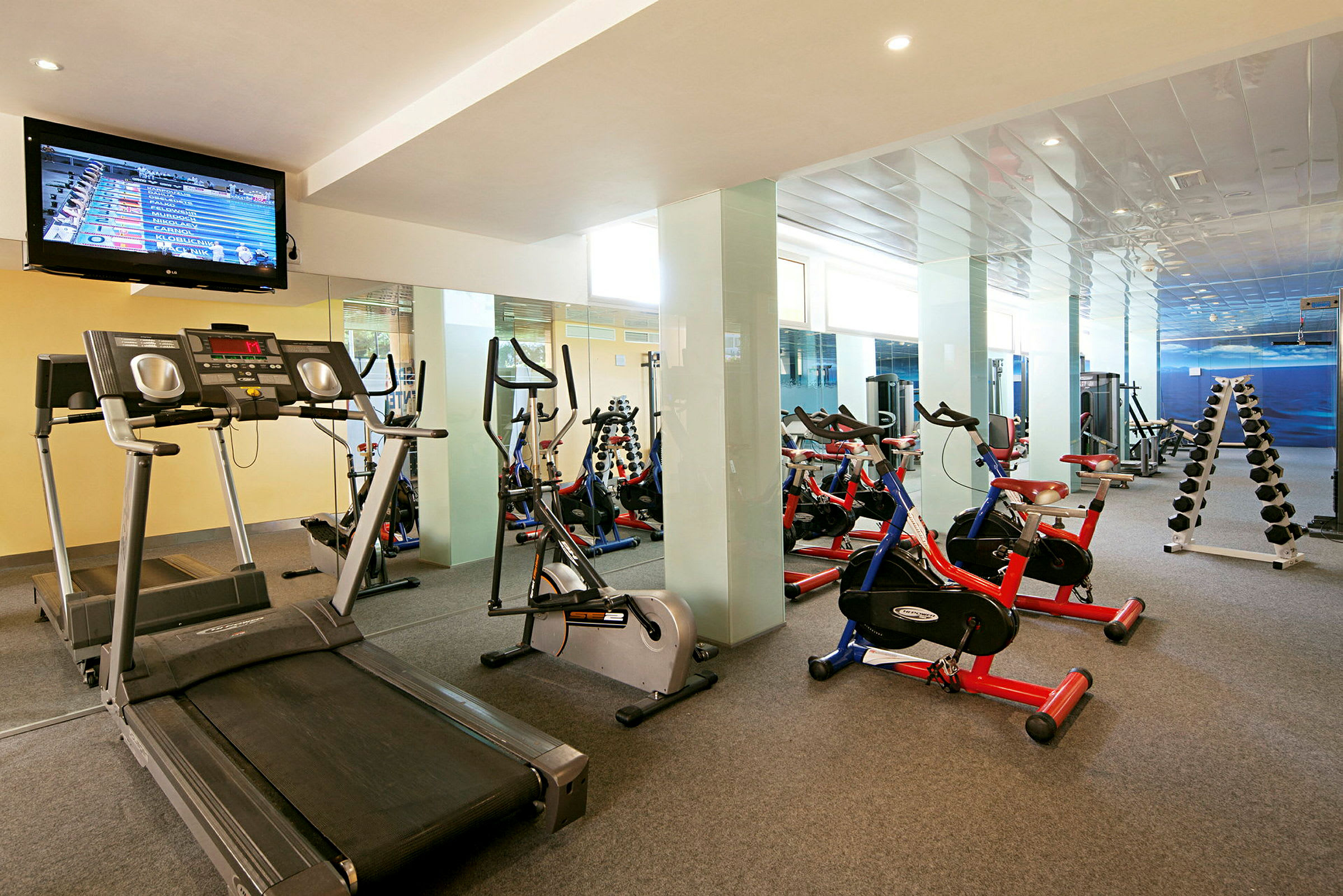 Et fitnesscenter med løbebånd, træningscykler og håndvægte. (AI-genereret tekst)