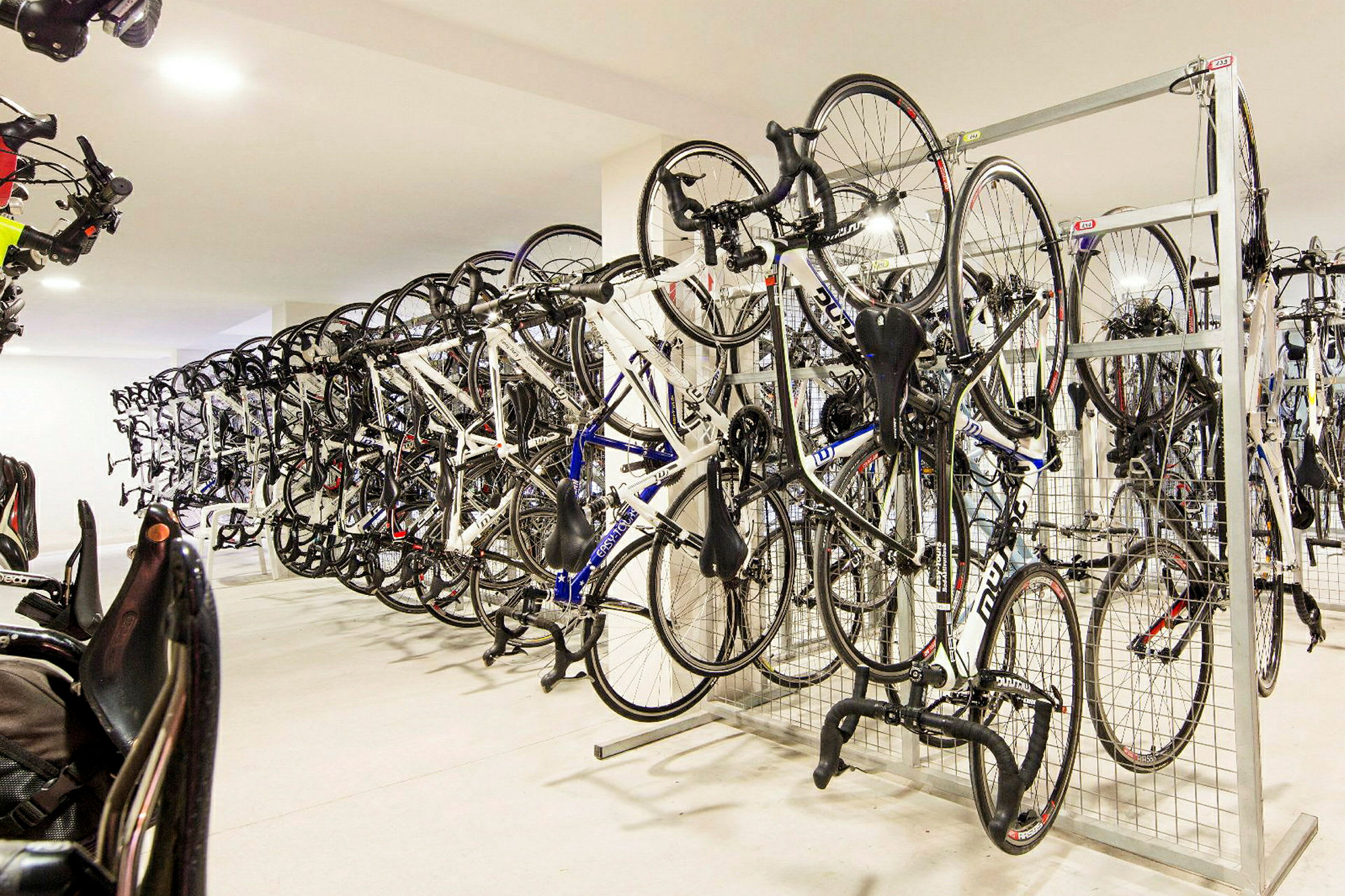 En cykelopbevaring med flere cykler hængende på stativ. (AI-genereret tekst)