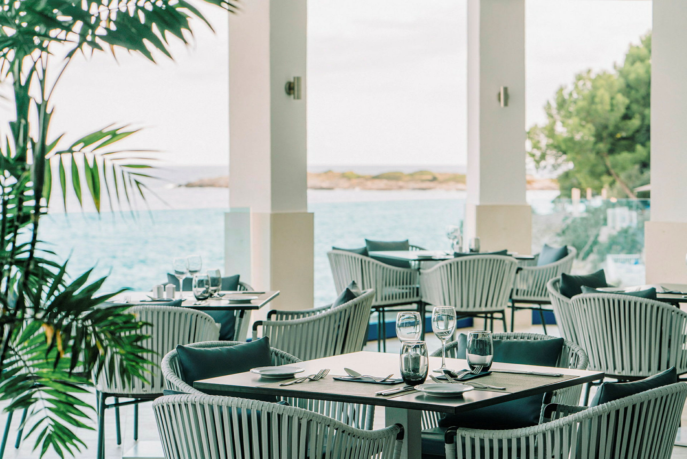 En udendørs restaurant med udsigt over havet og vegetationen. (AI-genereret tekst)