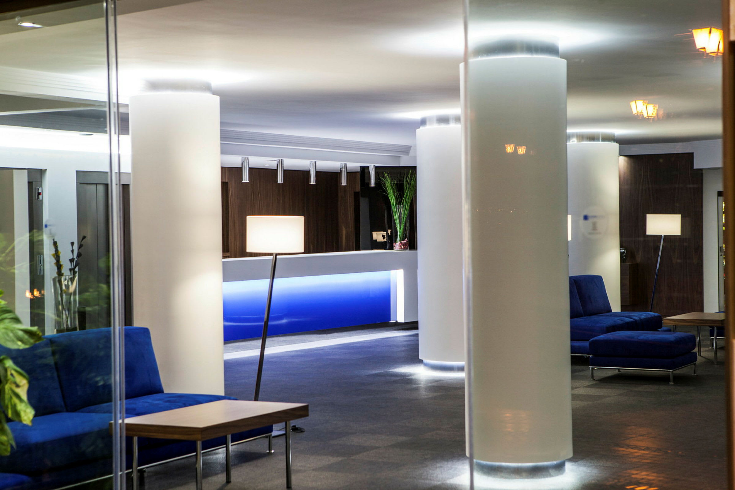En hotellobby med sofaer, borde og reception. (AI-genereret tekst)
