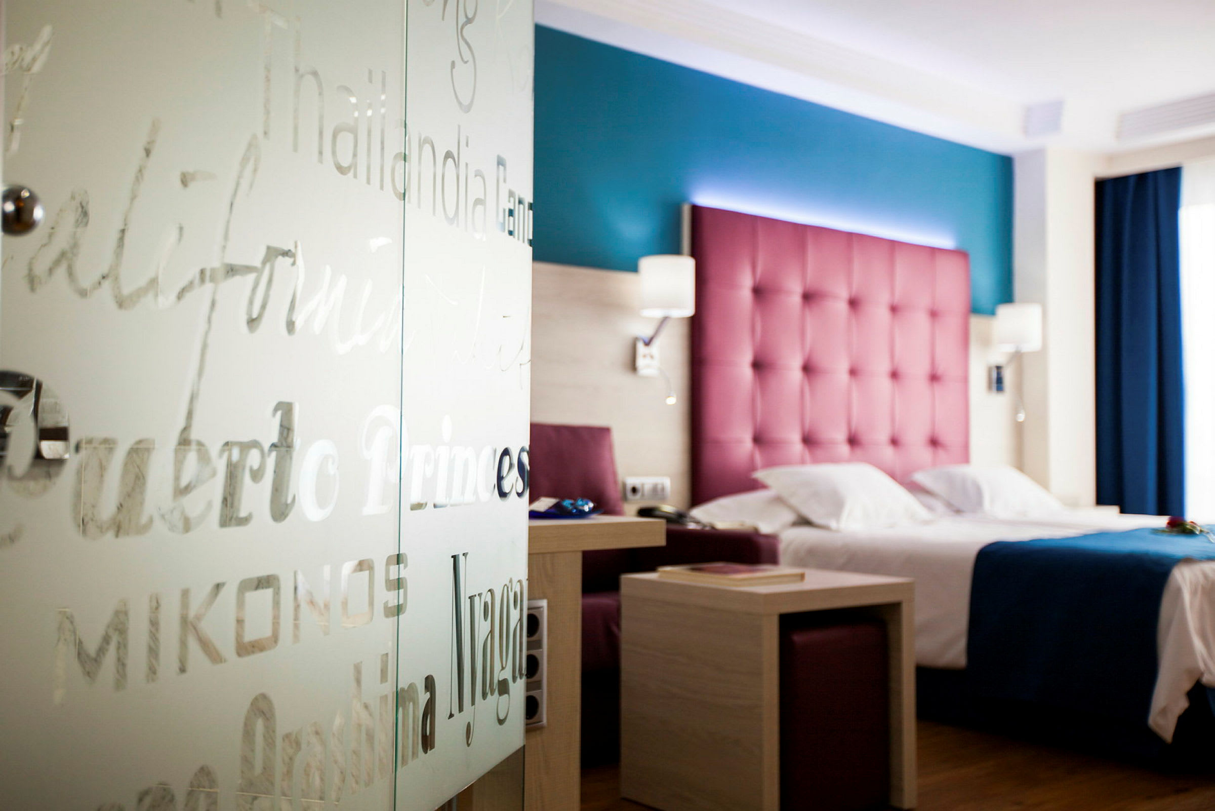 Hotelværelse med farverig indretning, seng og bord. (AI-genereret tekst)