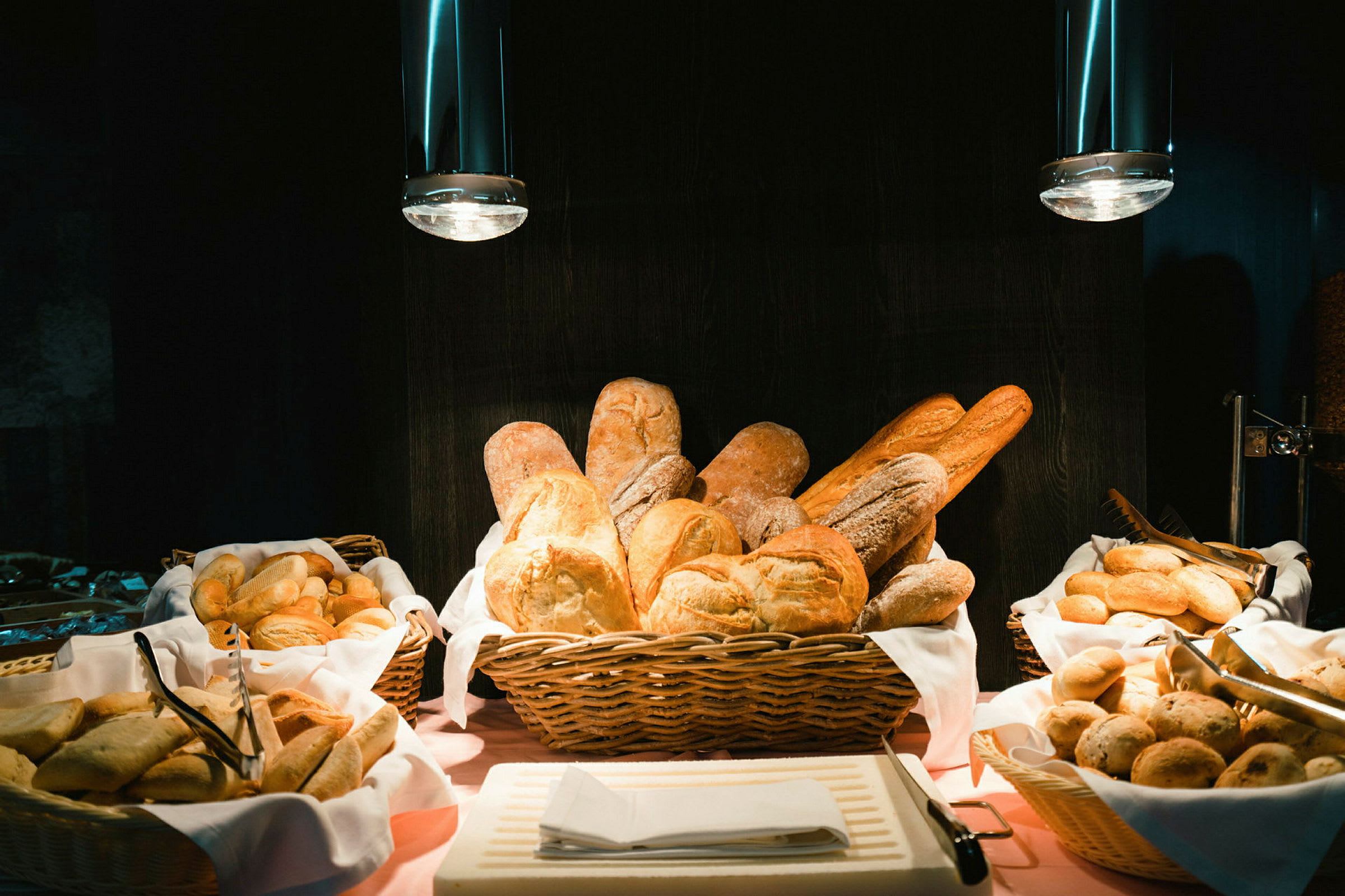 Forskellige slags brød i kurve på en buffet. (AI-genereret tekst)