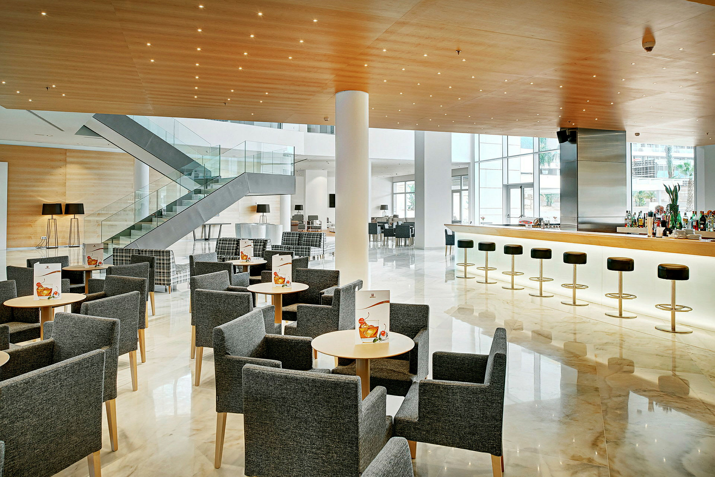 En moderne hotellobby med siddepladser, bar og trappe. (AI-genereret tekst)