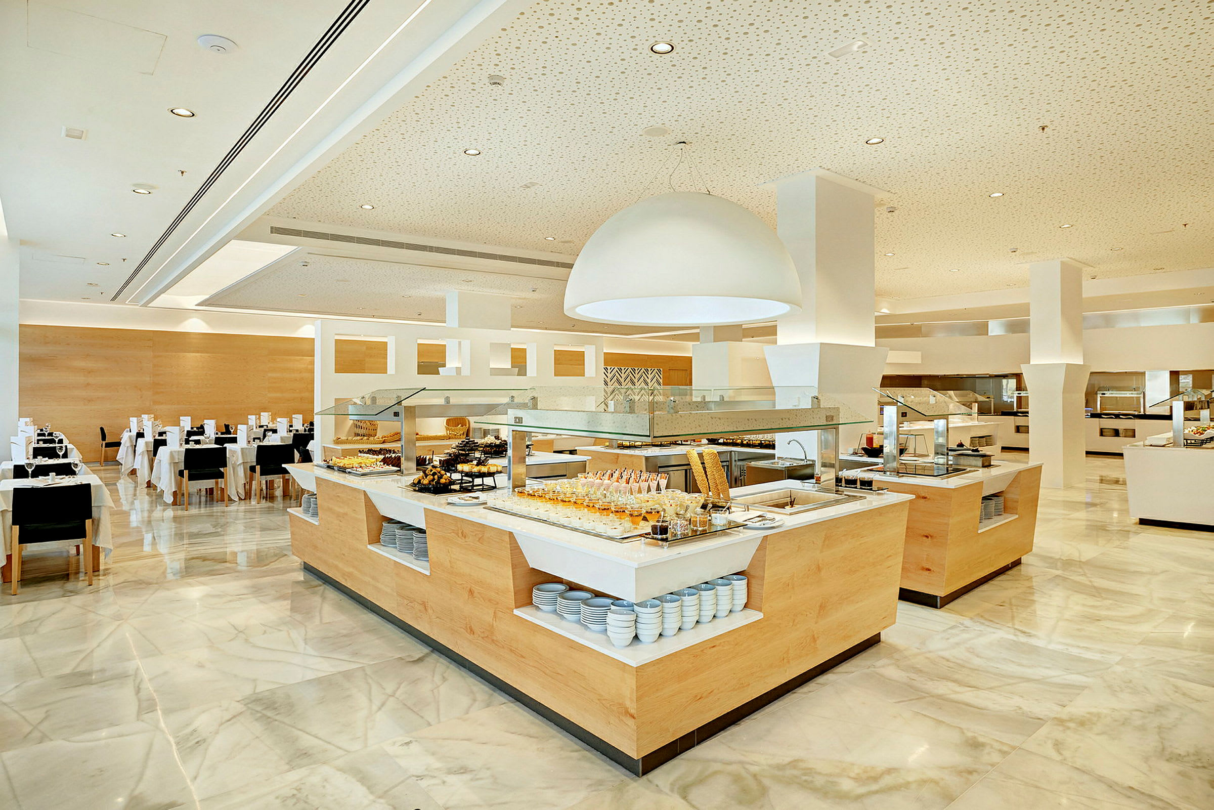 Buffetområde i en lys og moderne restaurant med tallerkener og mad opstillet. (AI-genereret tekst)