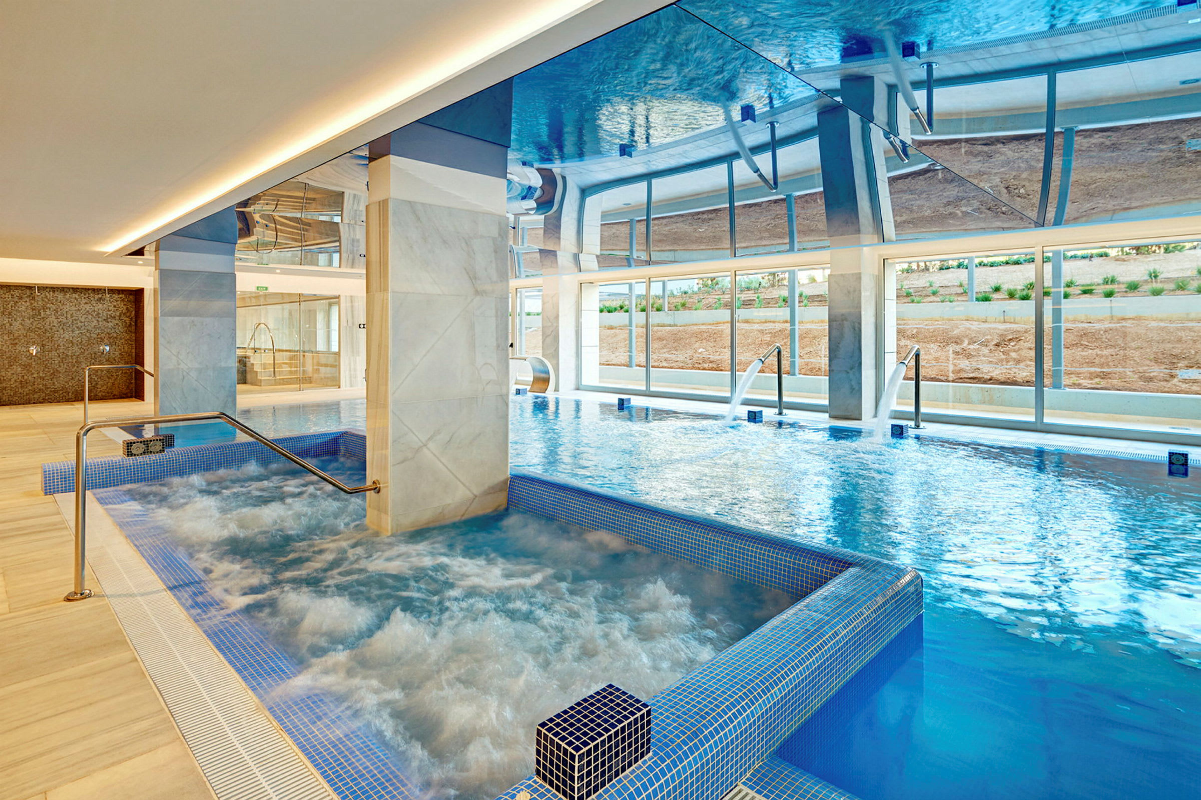 Indendørs pool med boblebad og vandstråler, omgivet af moderne marmorsøjler. (AI-genereret tekst)