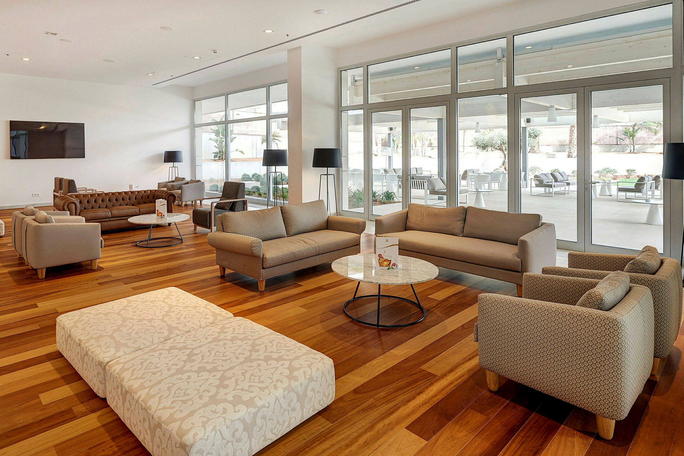 Billede af en rummelig og moderne lounge med sofaer, lænestole og borde. (AI-genereret tekst)