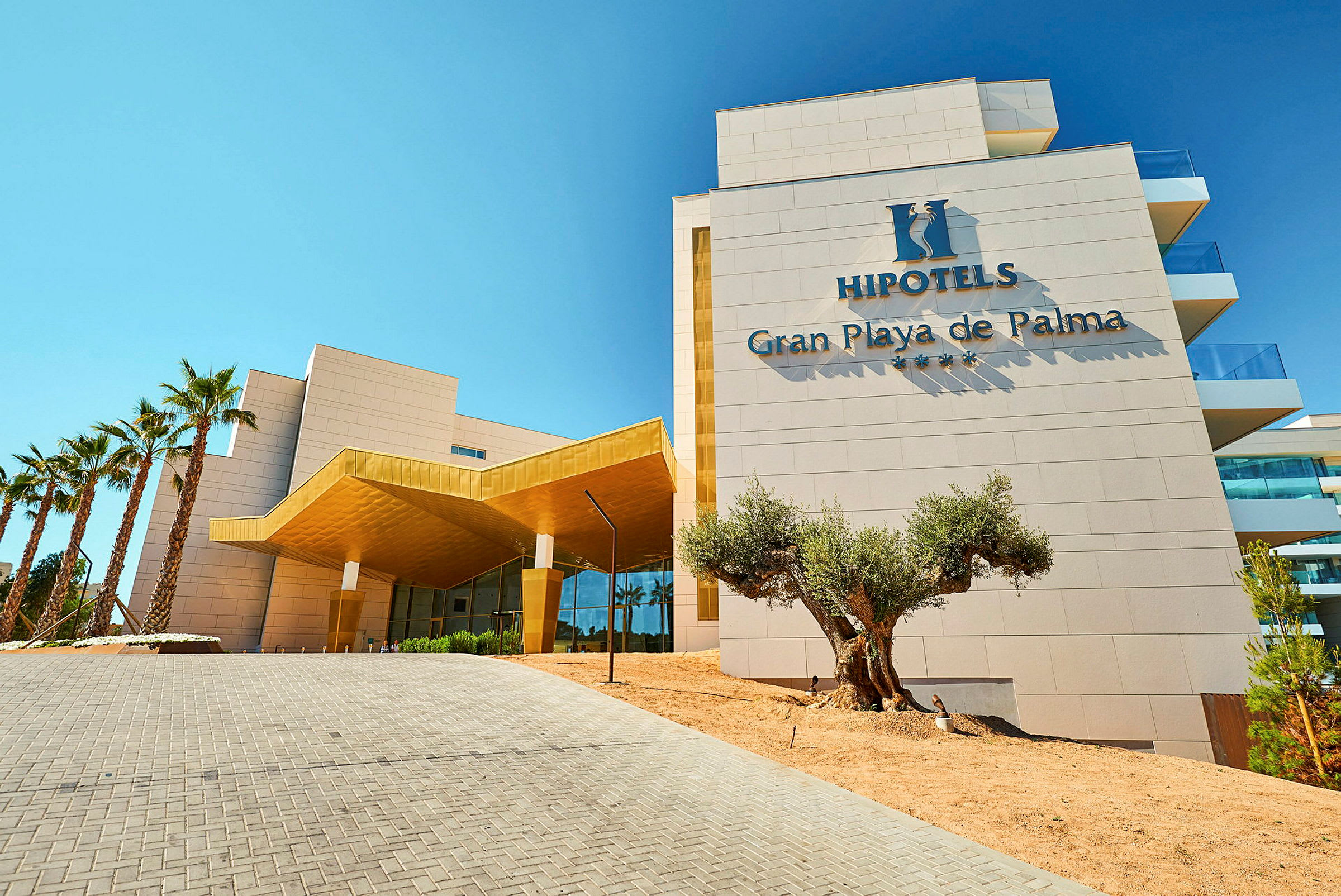 Den moderne hotelbygning Hipotel Gran Playa de Palma med palmer udenfor. (AI-genereret tekst)