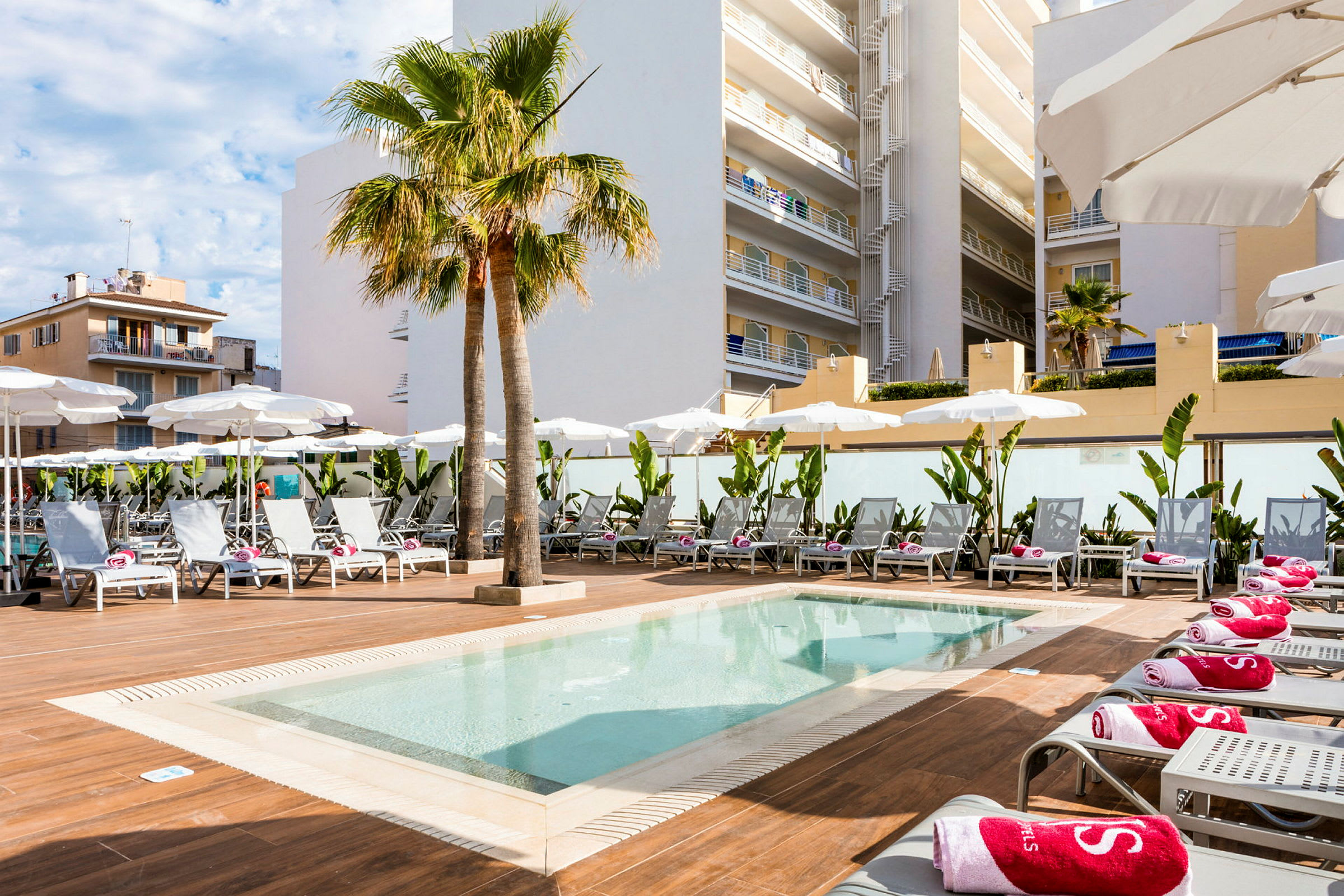 En pool med liggestole og parasoller ved et hotel. (AI-genereret tekst)