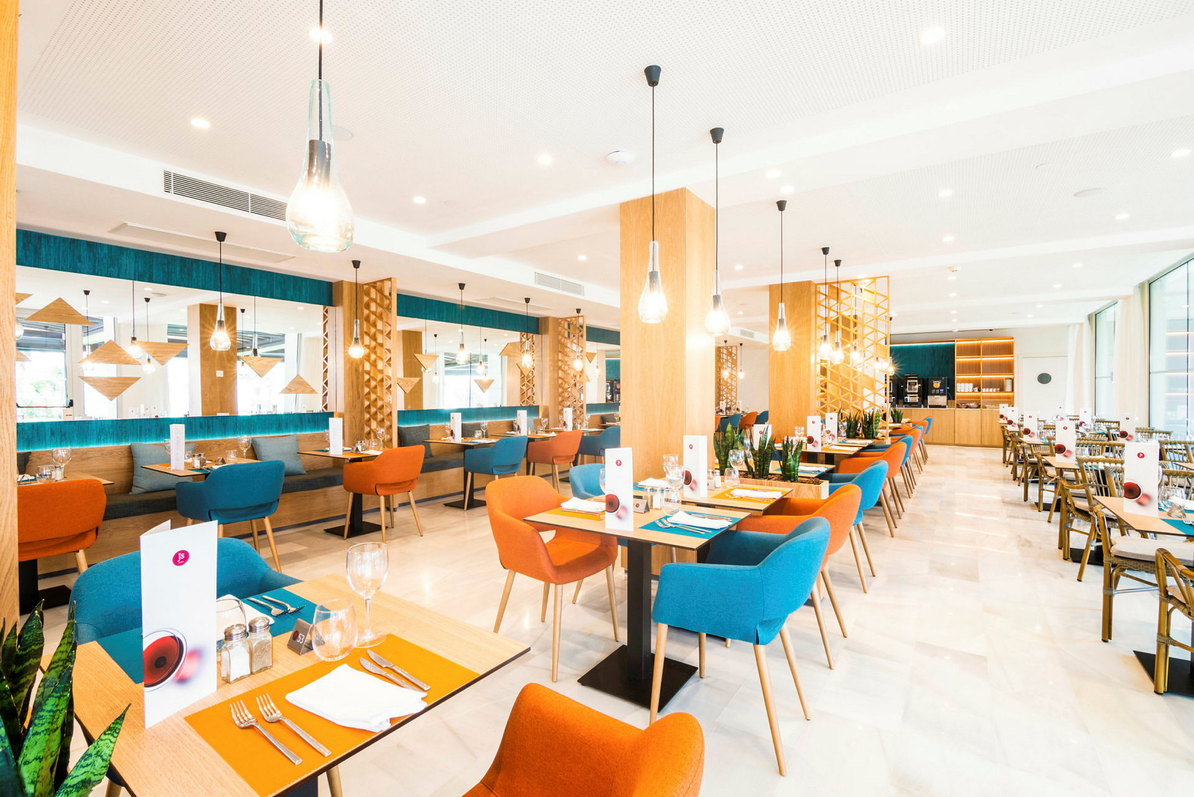 Billede af en moderne restaurant med farverige stole, træborde og dekorative lysarmaturer. (AI-genereret tekst)