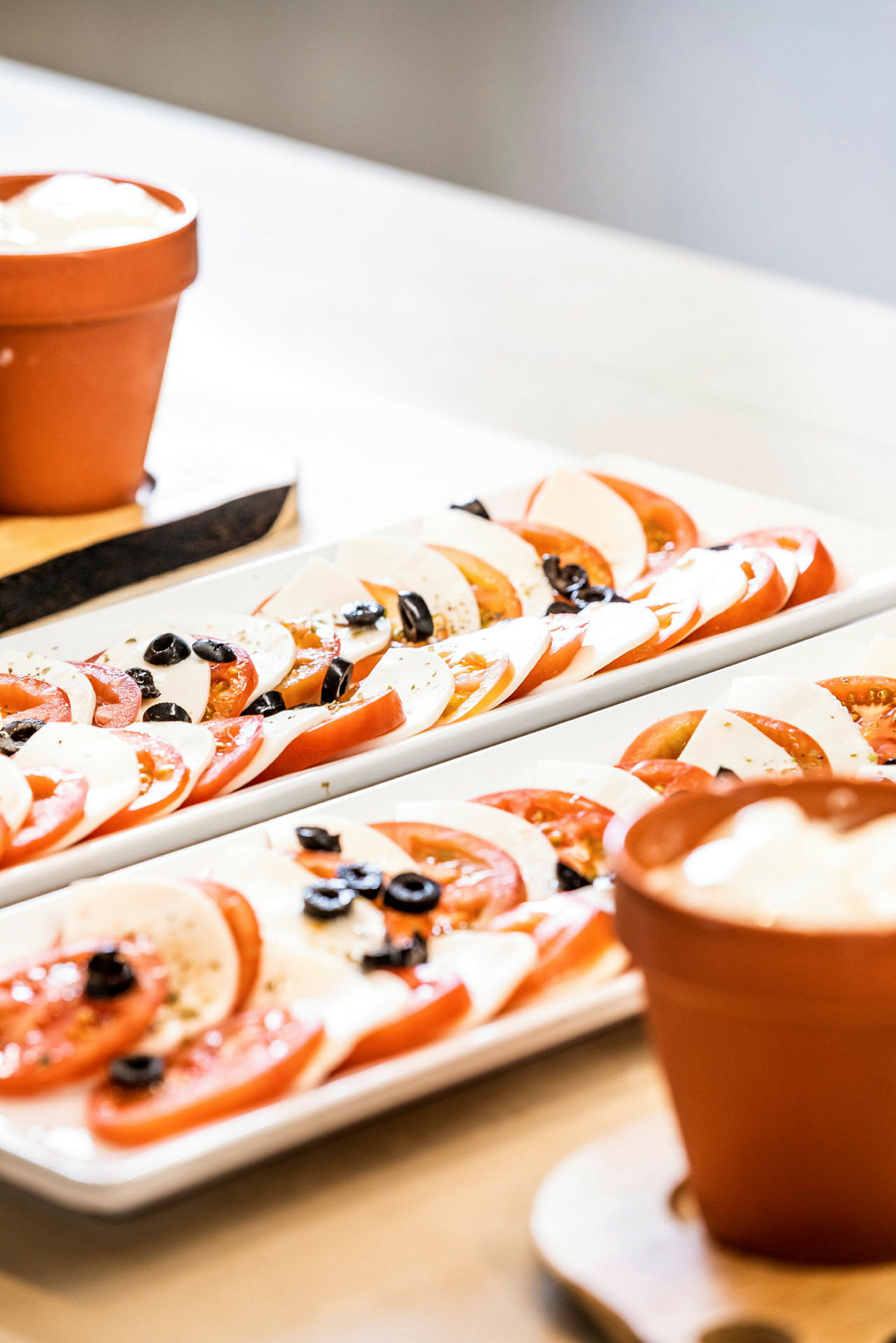 Nærbillede af tallerkener med skiver af tomat, mozzarella og oliven. (AI-genereret tekst)
