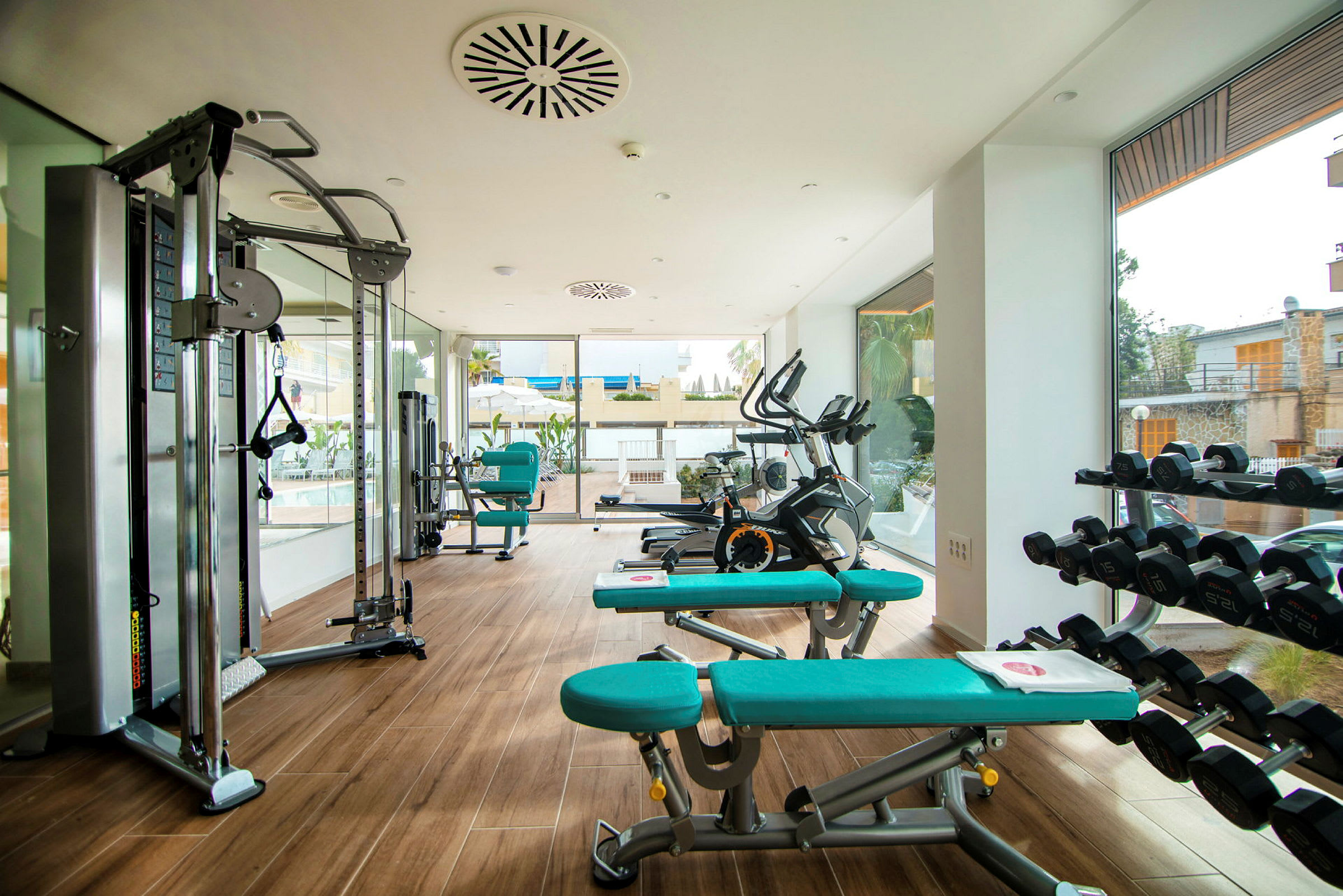 Et fitnesscenter med træningsmaskiner, håndvægte og bænke i et lyst og moderne rum. (AI-genereret tekst)