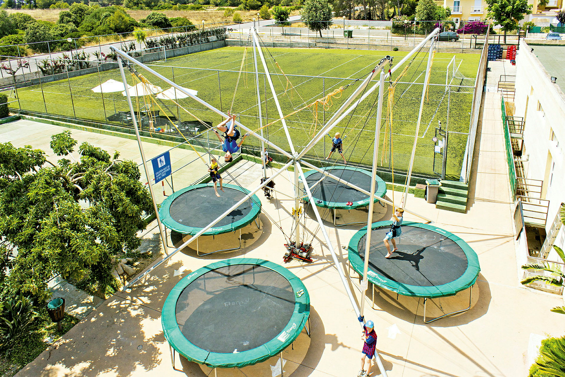 Flere personer hopper på trampoliner i en udendørspark. (AI-genereret tekst)