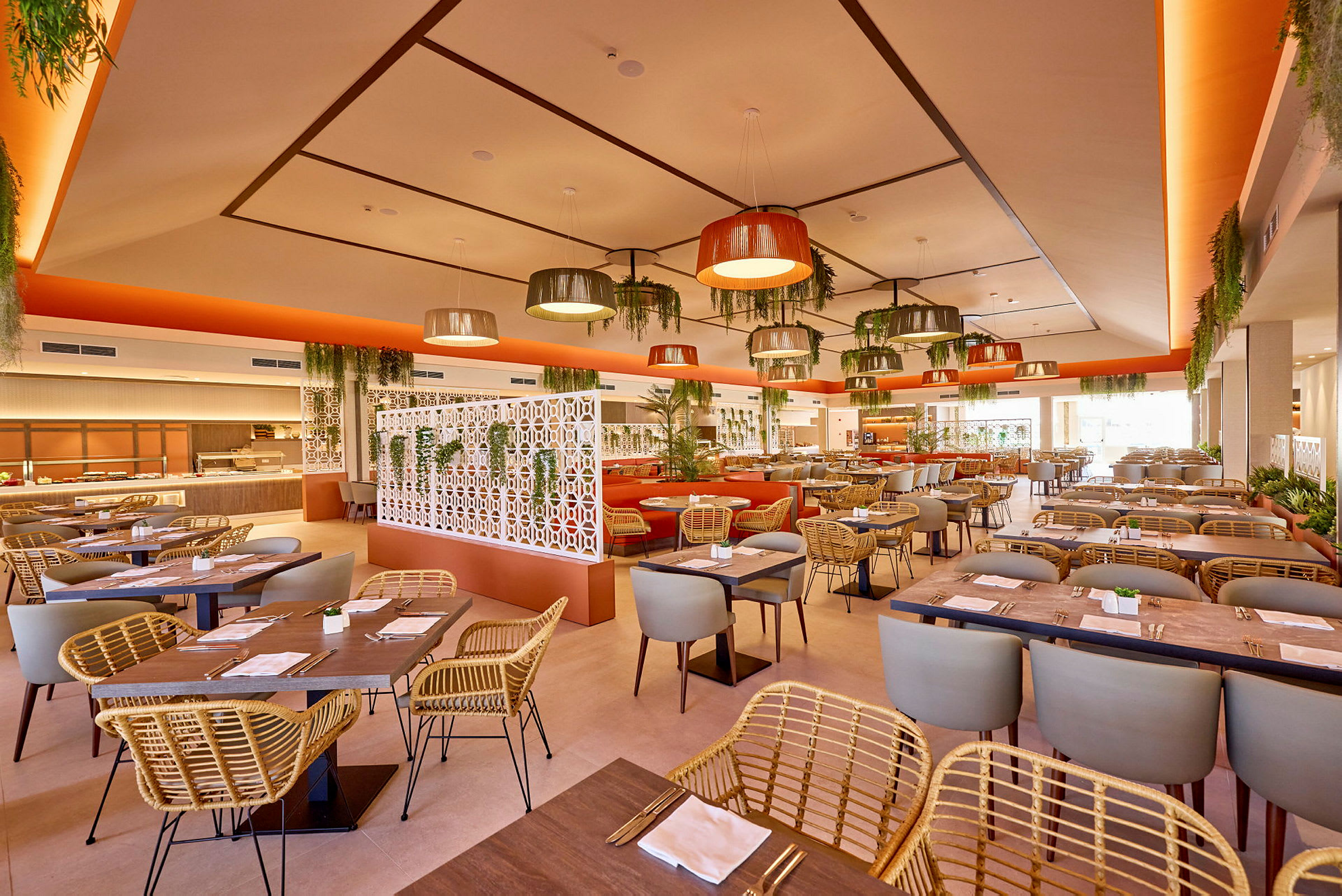En lys restaurant med moderne møbler og dekoration, inklusive hængende lamper og mange planter. (AI-genereret tekst)
