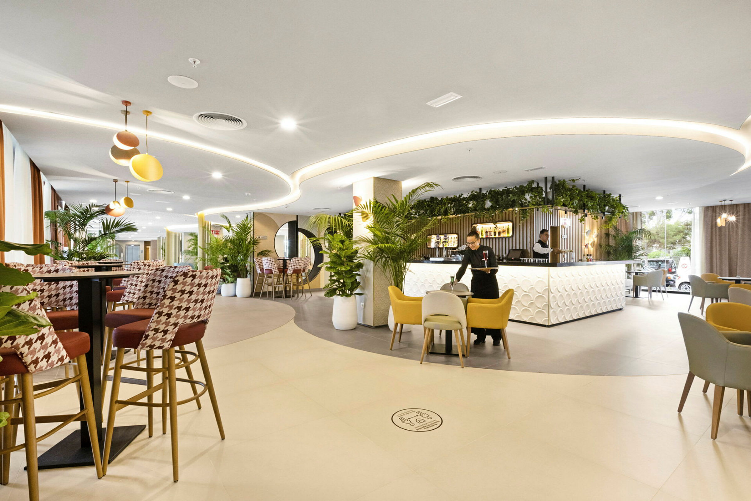 En modern hotelatrium med stilfuld indretning, siddeområder og planteudsmykning. (AI-genereret tekst)