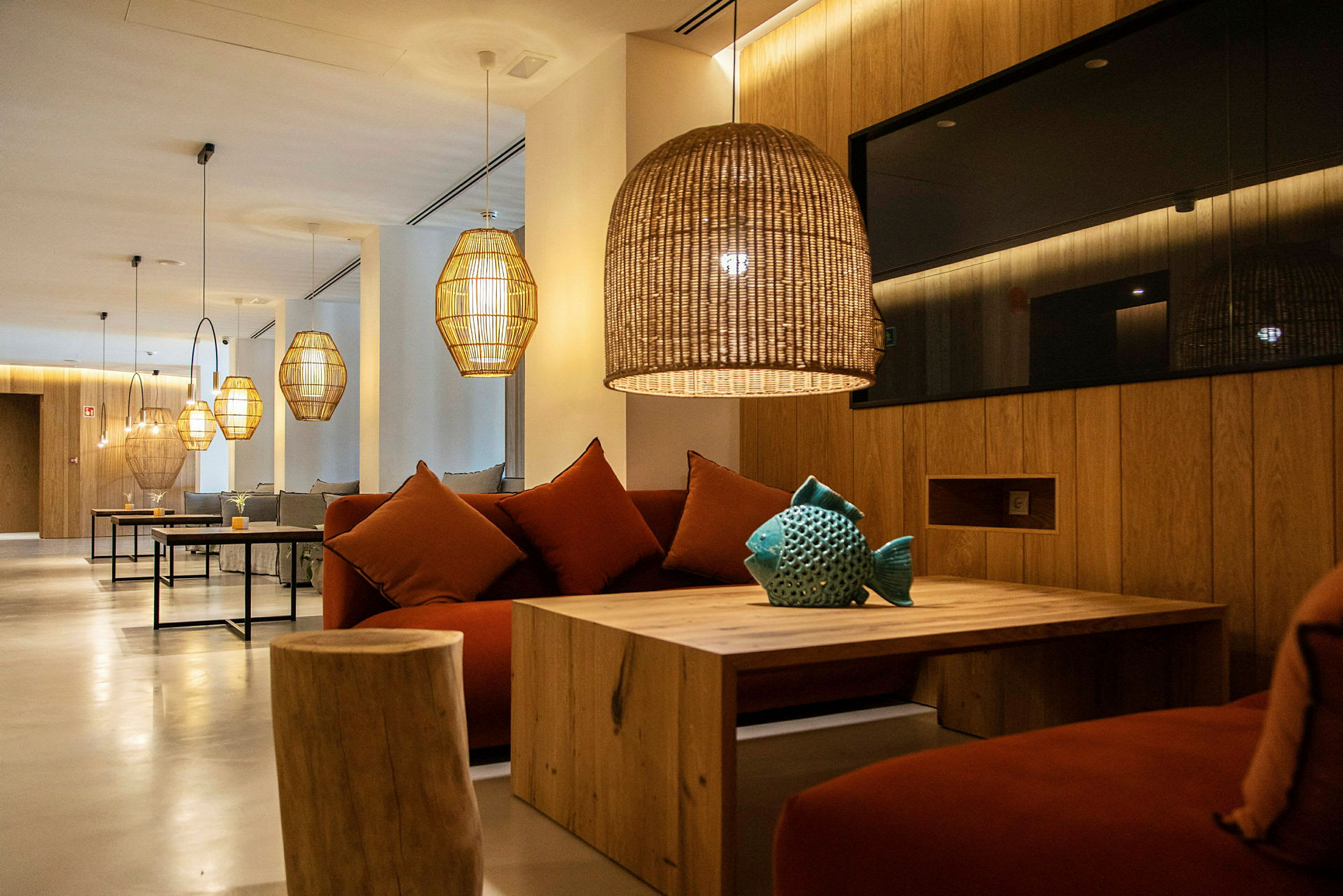 Moderne lounge med sofaer, træborde og hængende lamper. (AI-genereret tekst)