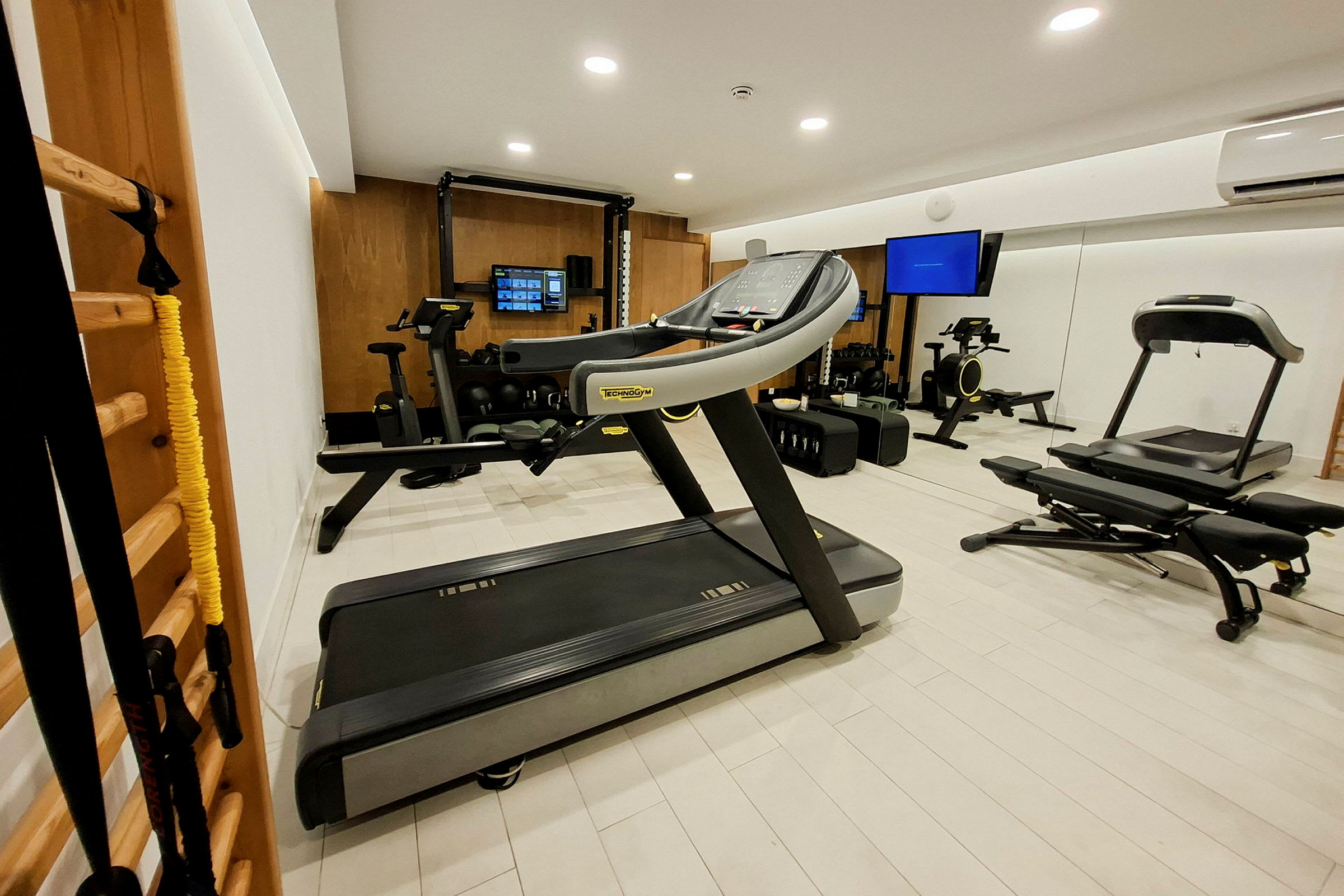 Et moderne fitnesscenter med træningsmaskiner, løbebånd og spejlvæg. (AI-genereret tekst)