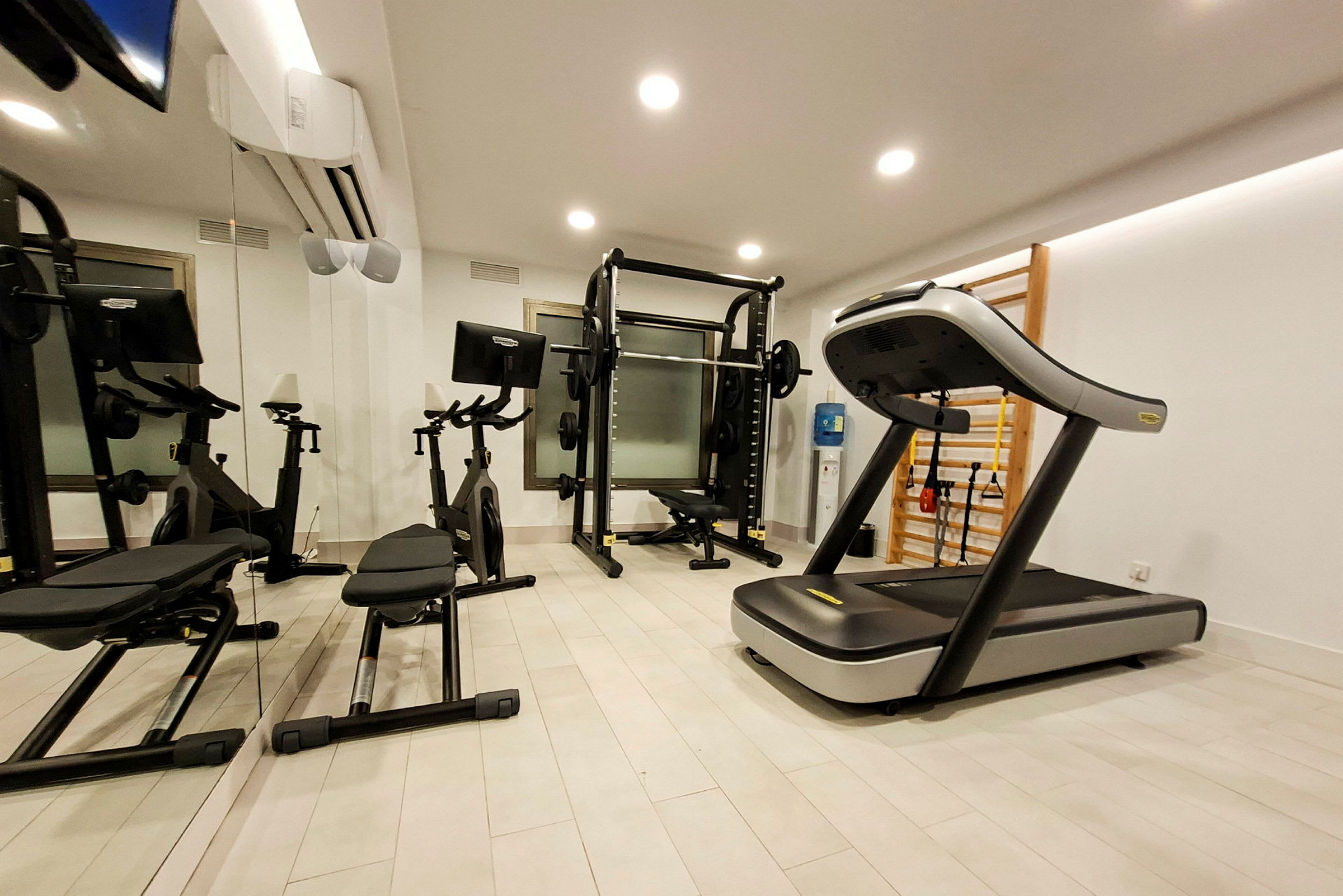 Et fitnesscenter med træningsmaskiner inklusive et løbebånd, motionscykler og styrketræningsudstyr. (AI-genereret tekst)