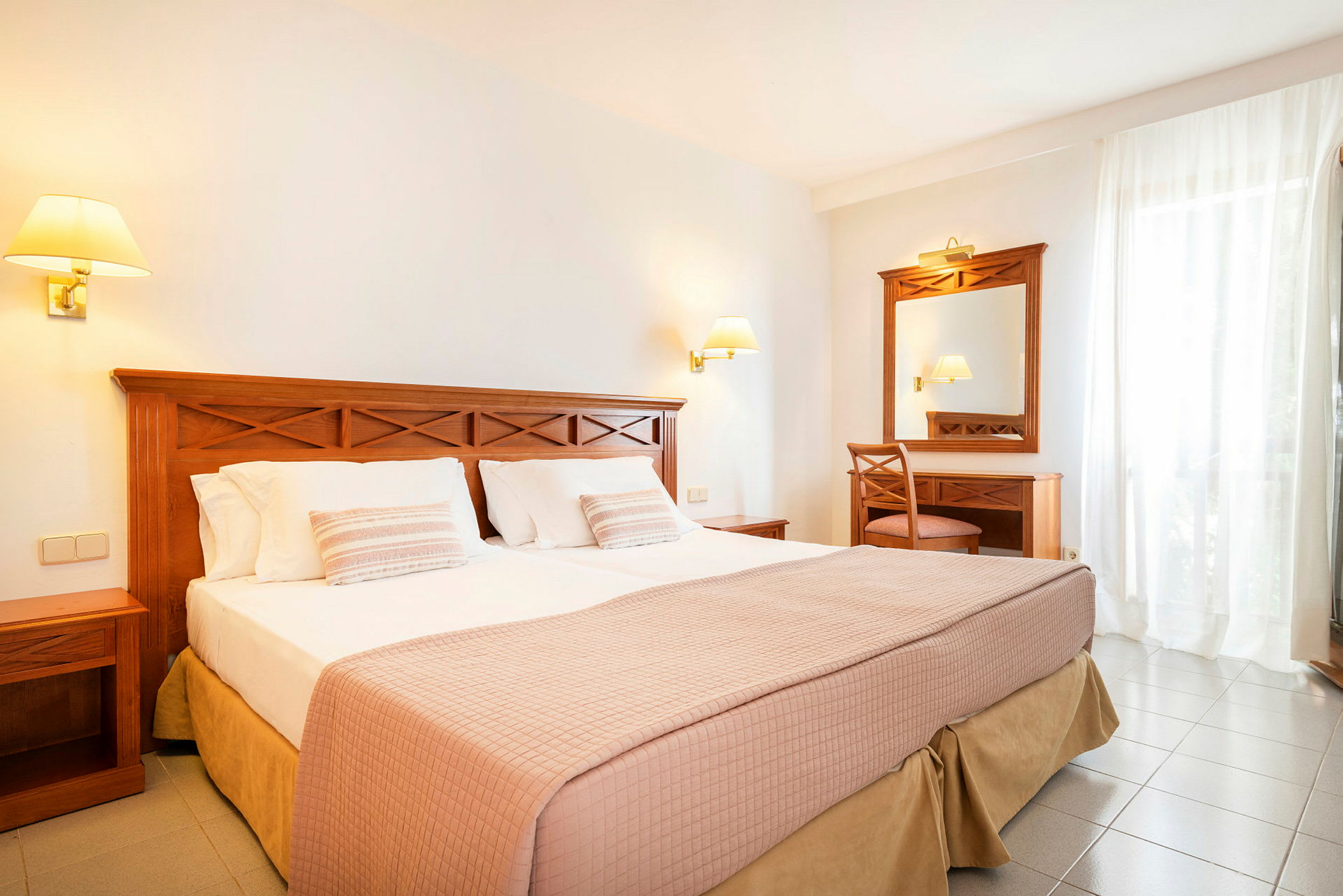 Hotelværelse med dobbeltseng, natbord og skrivebord med spejl. (AI-genereret tekst)