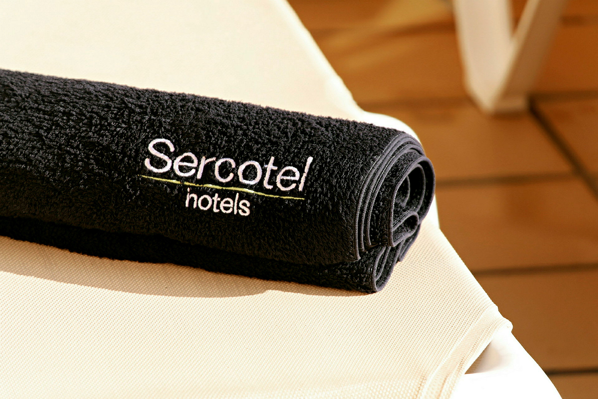 Et sort håndklæde med teksten 'Sercotel hotels' broderet, placeret på en lys flade. (AI-genereret tekst)