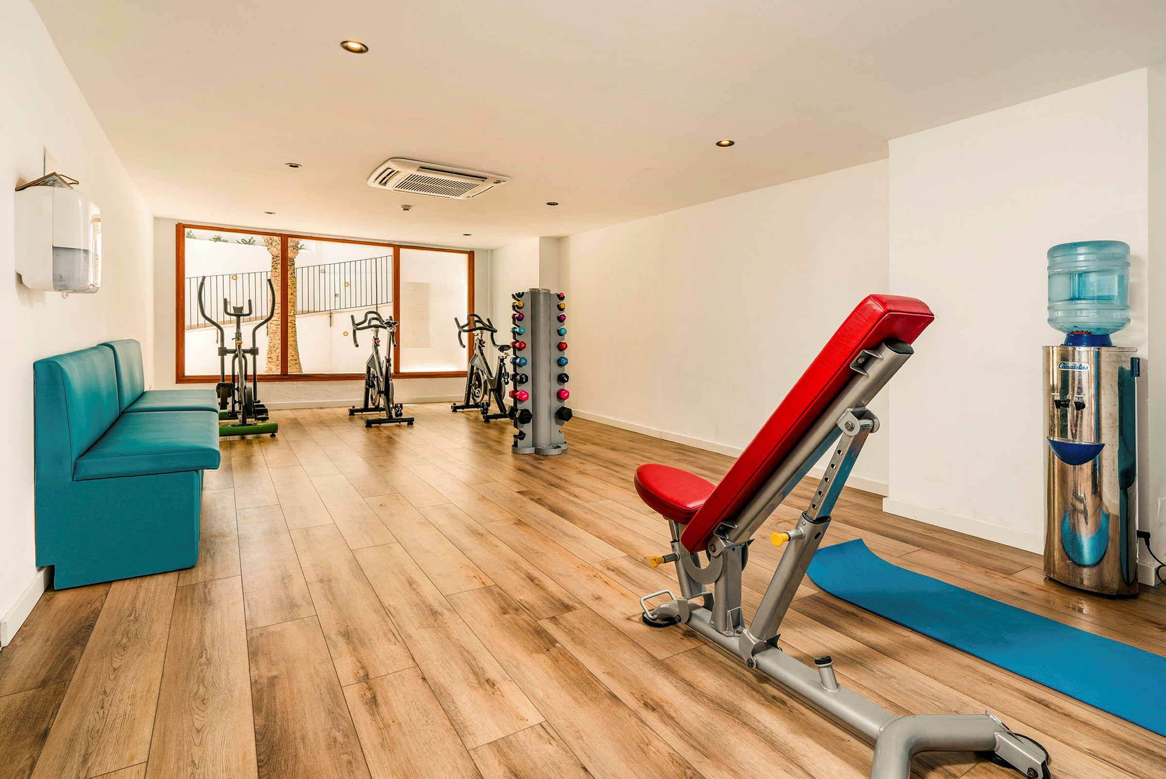 Et fitnessrum med træningsudstyr, en bænk og håndvægte. (AI-genereret tekst)