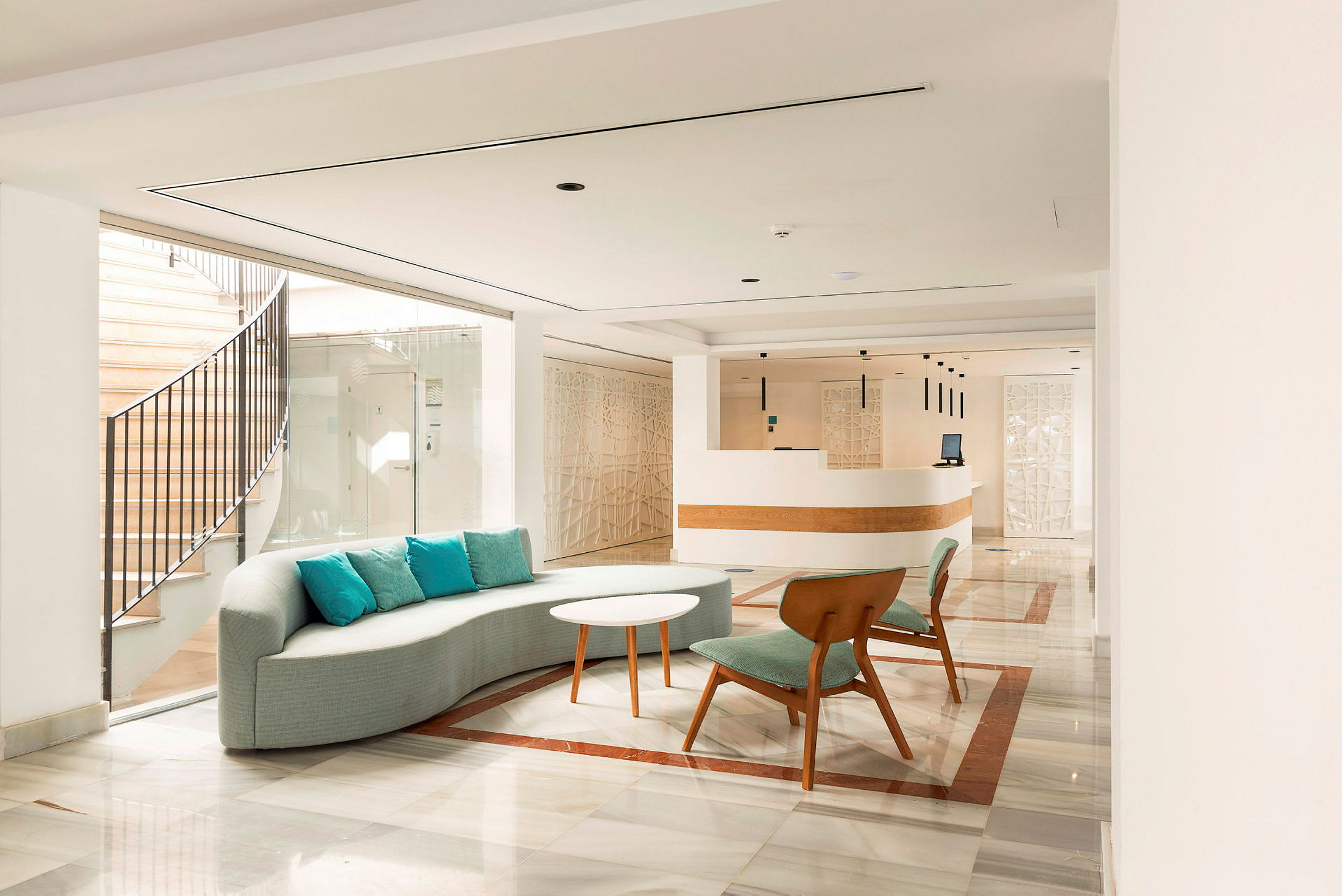Lys hotellets lobby med moderne indretning, siddepladser og en reception. (AI-genereret tekst)