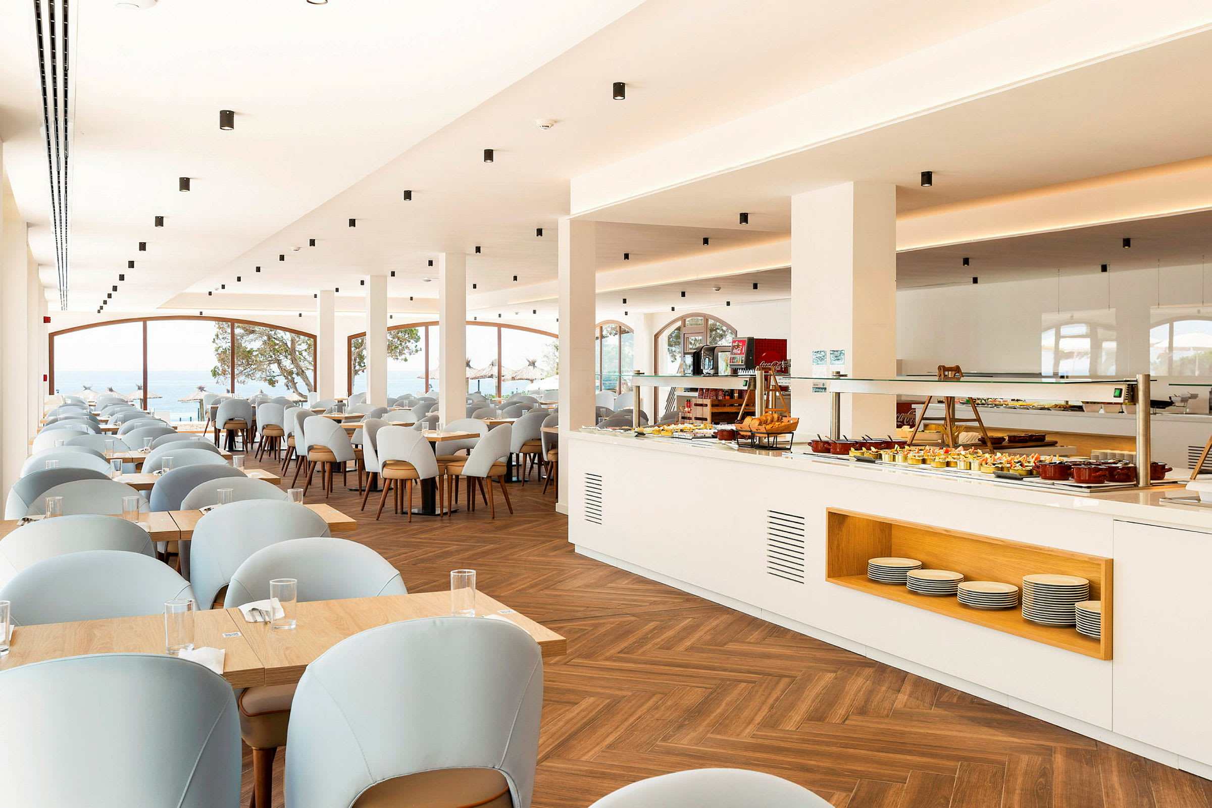 En lys restaurant med borde og stole samt en buffet. (AI-genereret tekst)
