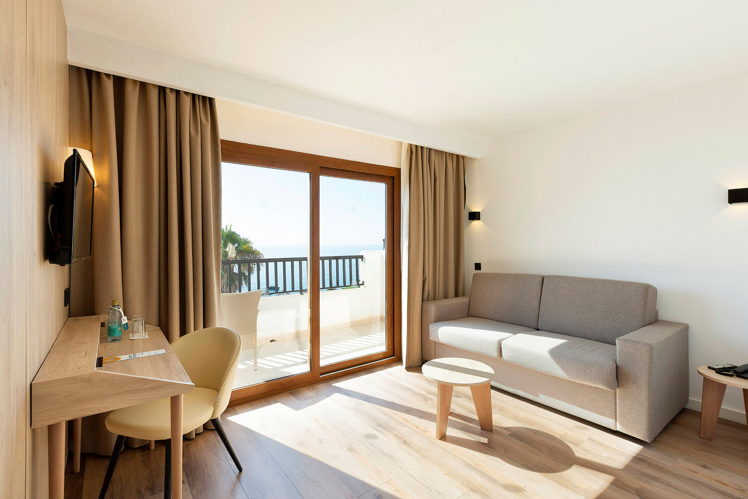 Moderne indrettet hotelværelse med siddeområde og udsigt til havet. (AI-genereret tekst)
