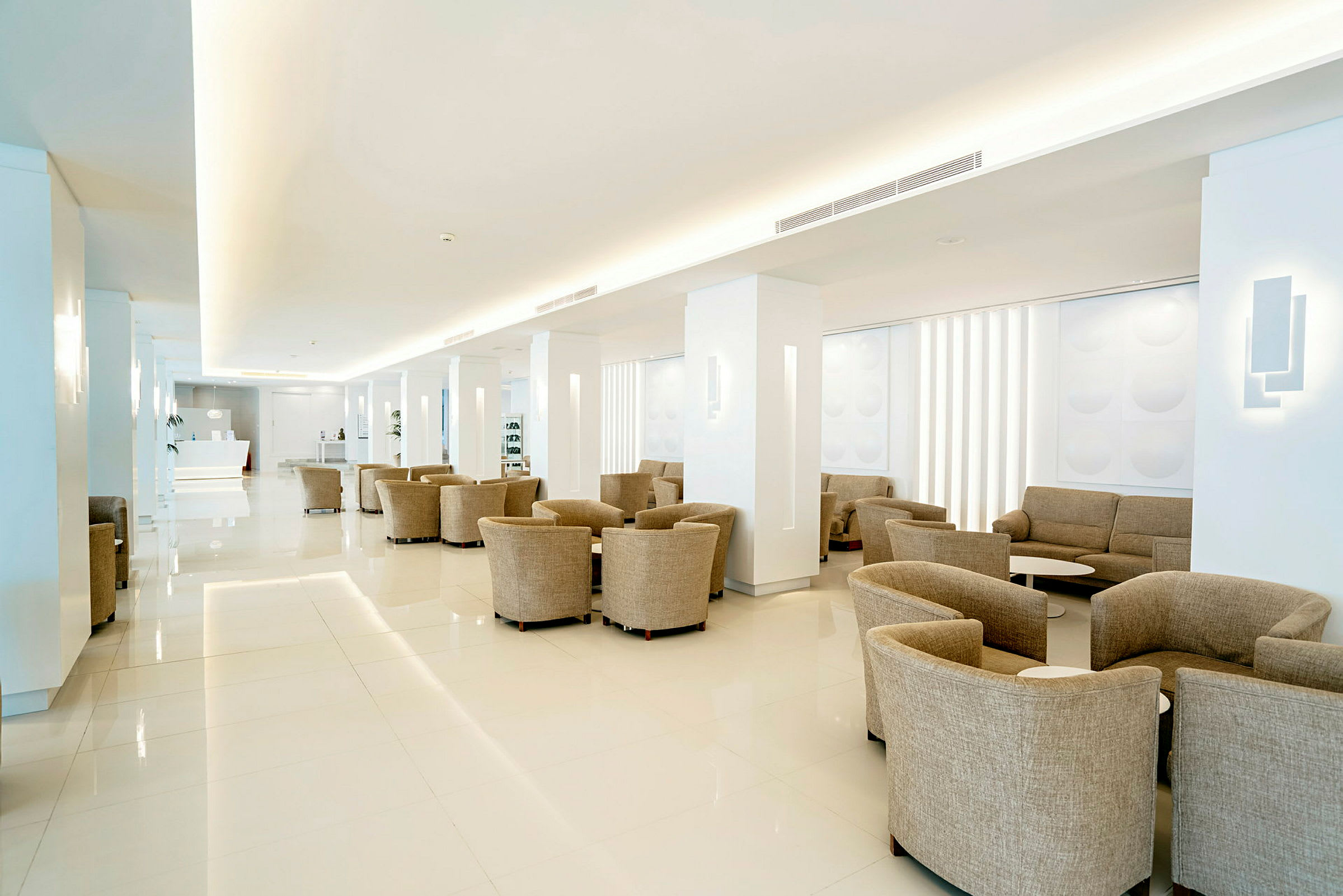 En rummelig og lys hotellobby med beige siddepladser. (AI-genereret tekst)