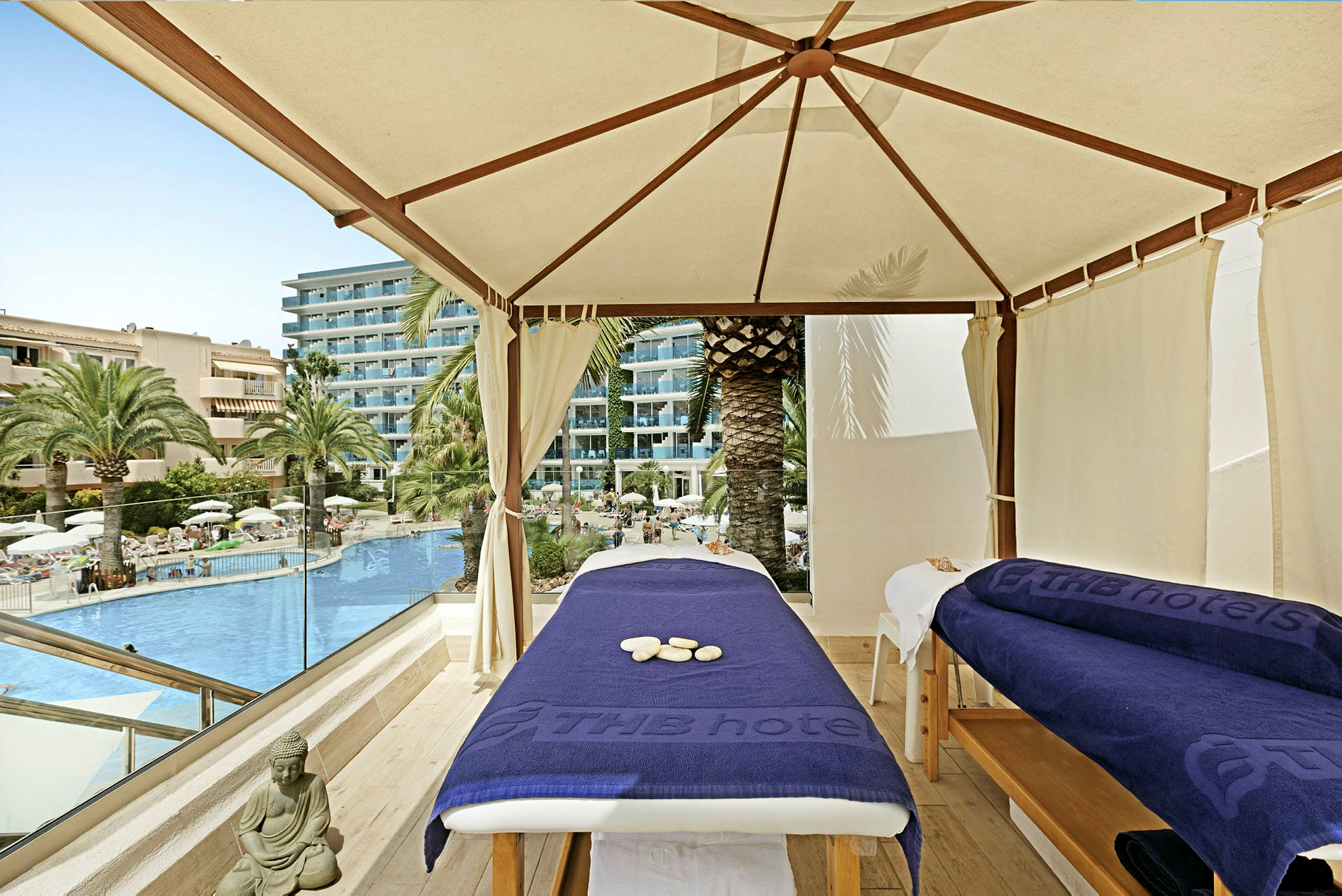To massageborde under en teltlignende struktur ved en hotelpool. (AI-genereret tekst)