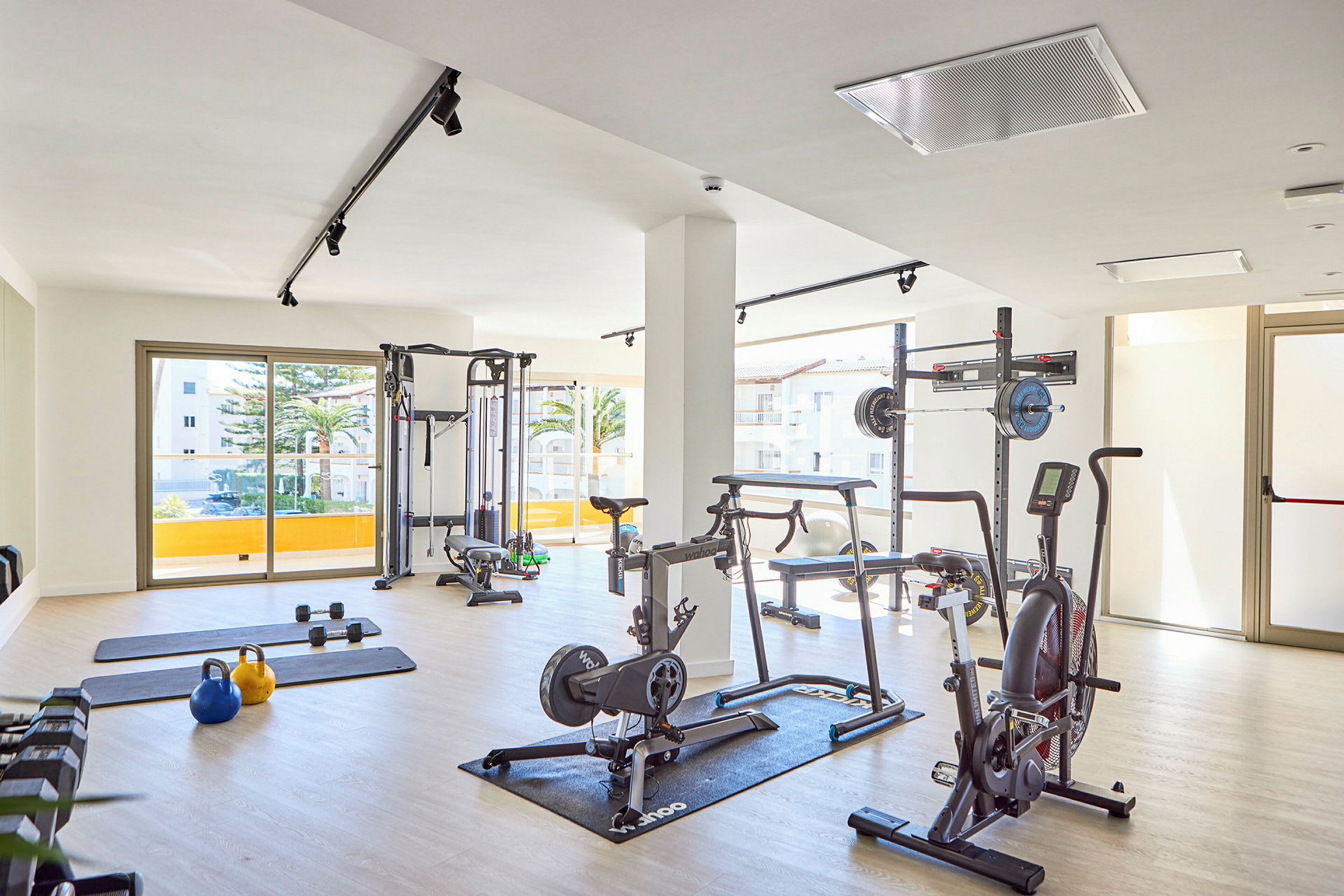 Et fitnesscenter med forskellige træningsredskaber placeret i et lyst rum. (AI-genereret tekst)