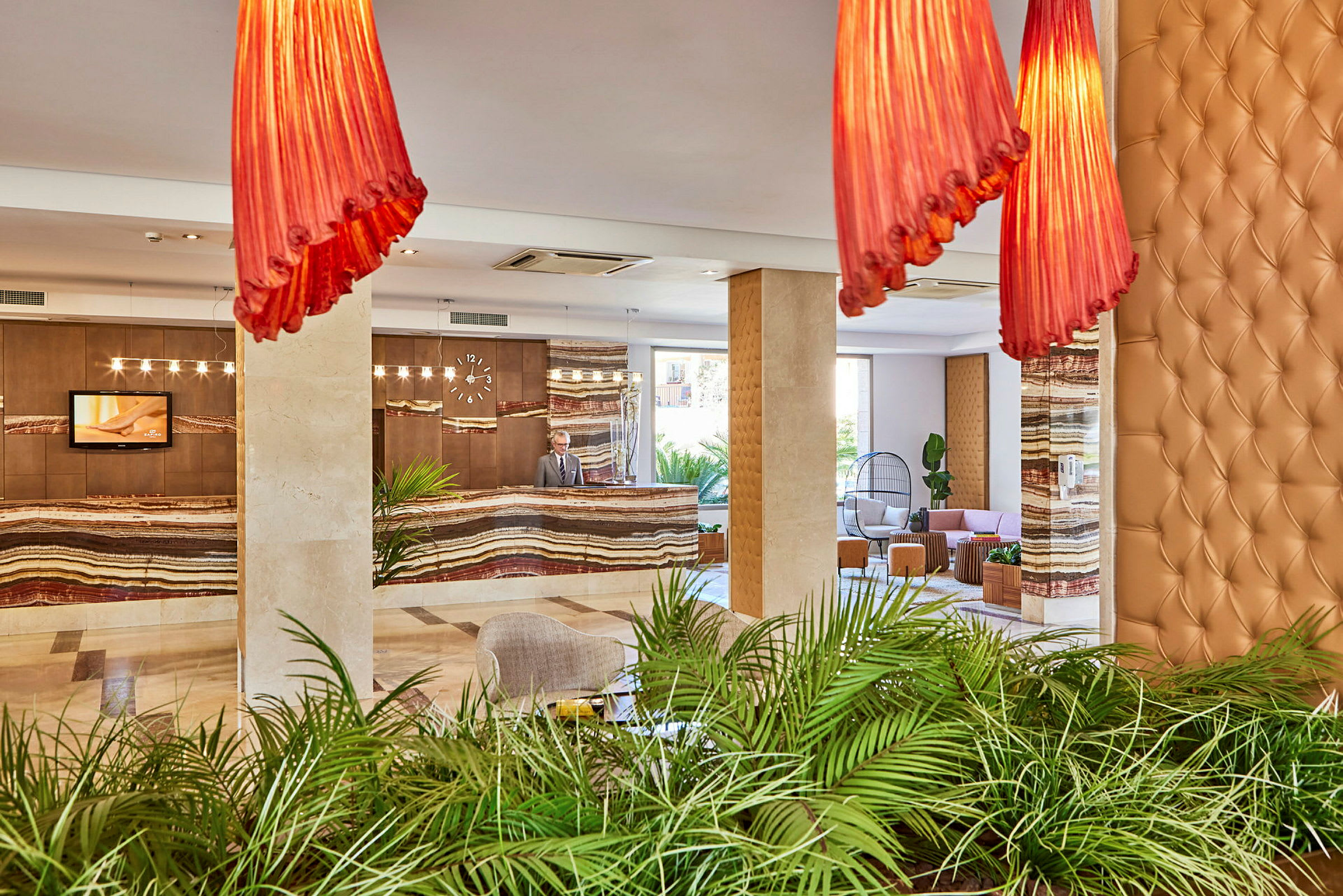 Hotel lobby med reception, grønne planter og siddeområder. (AI-genereret tekst)