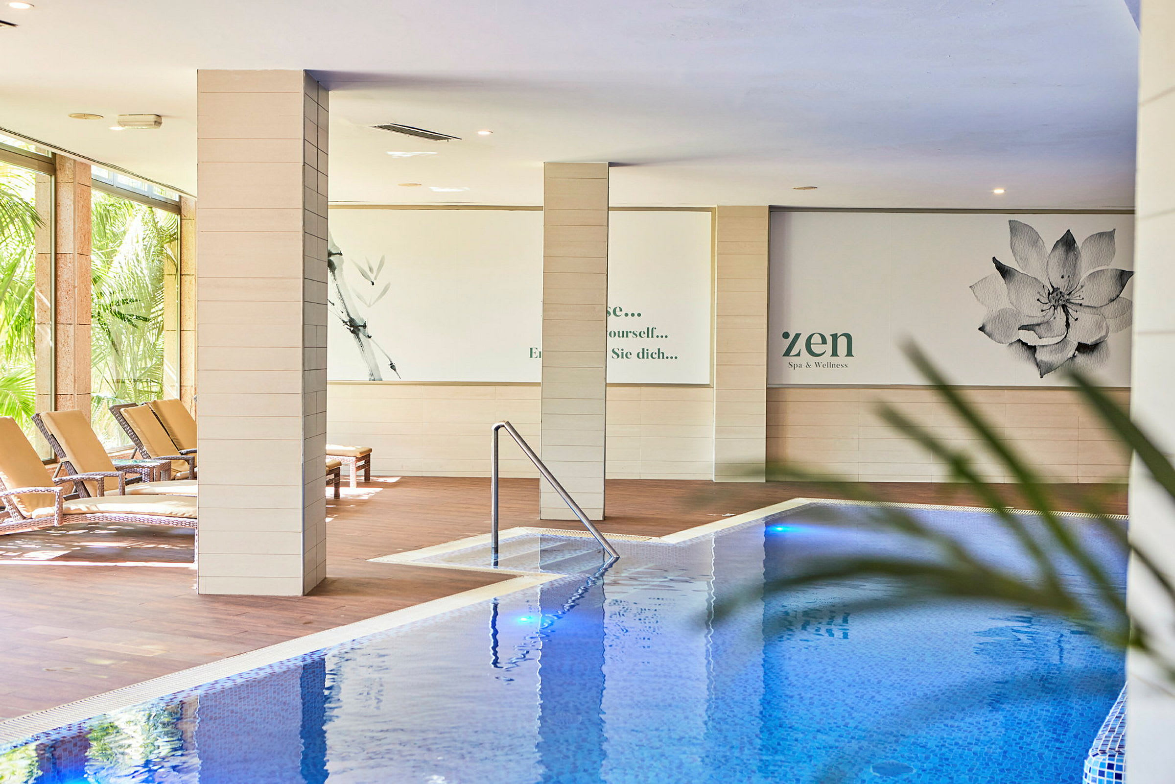 Indendørs swimmingpool med liggestole ved siden af og vægdekorationer inspireret af spa-tema. (AI-genereret tekst)