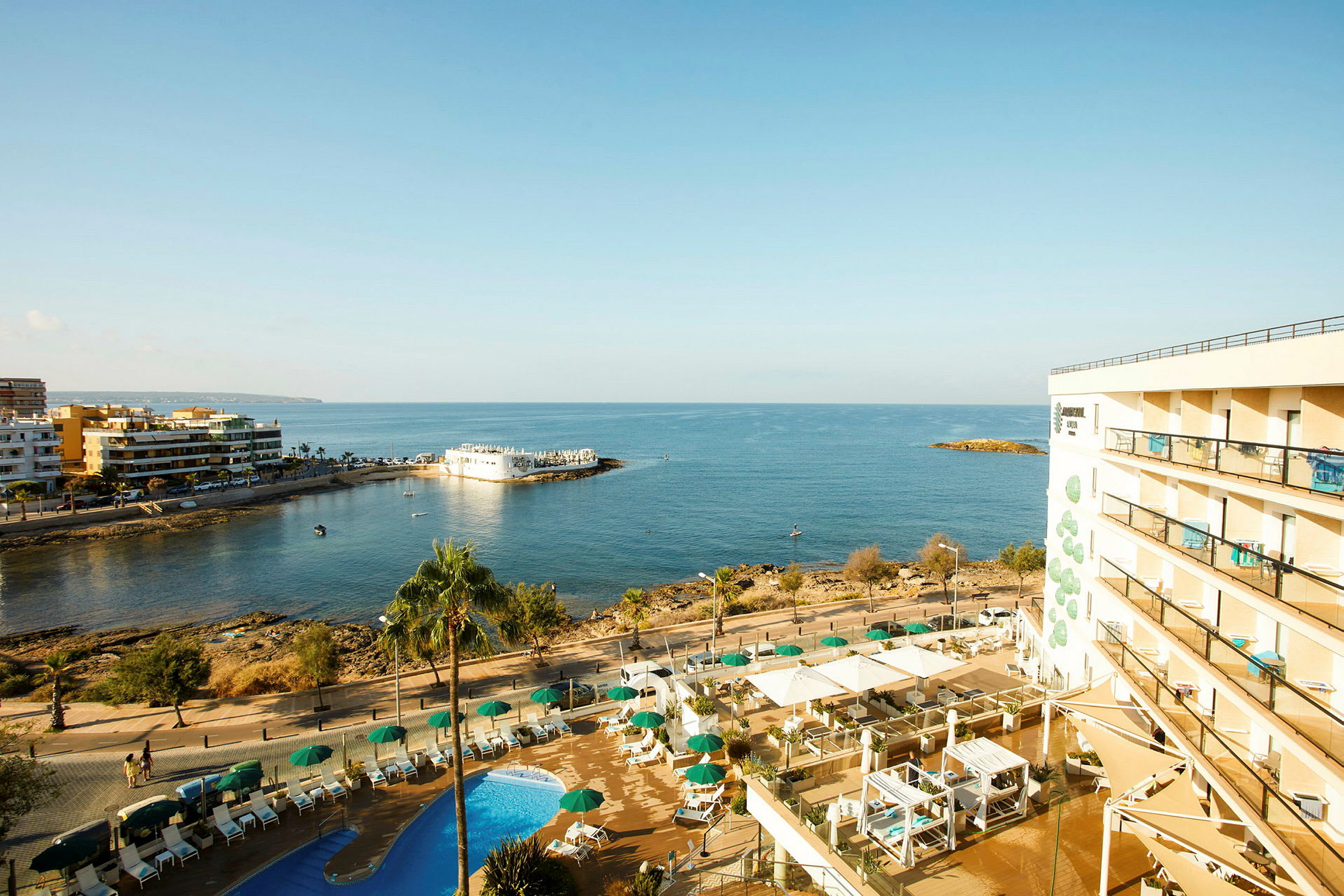 Hotellet med pools og udsigt over havet og kystlinjen. (AI-genereret tekst)