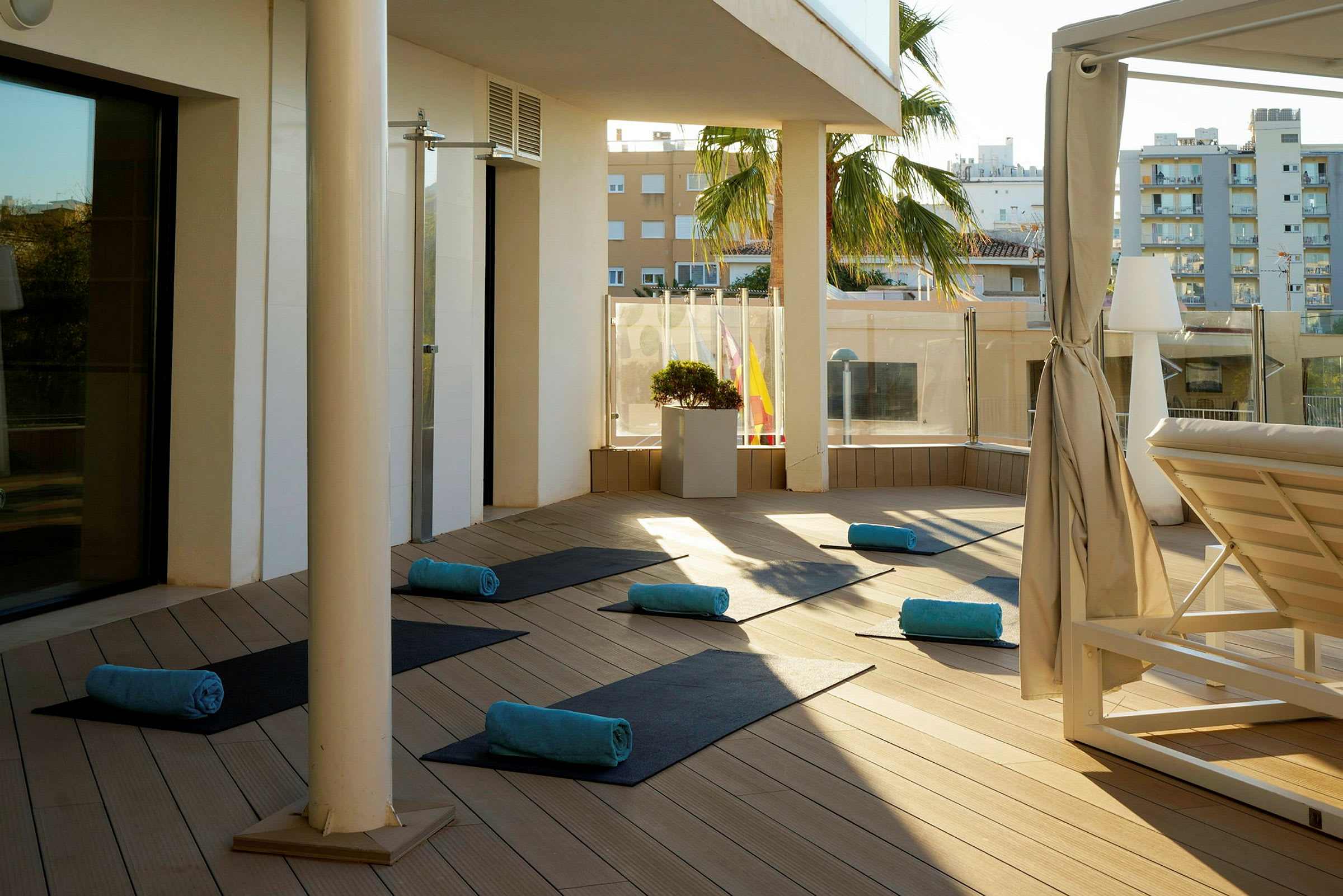 Solbelyst terrasse med yogamåtter og håndklæder lagt ud. (AI-genereret tekst)