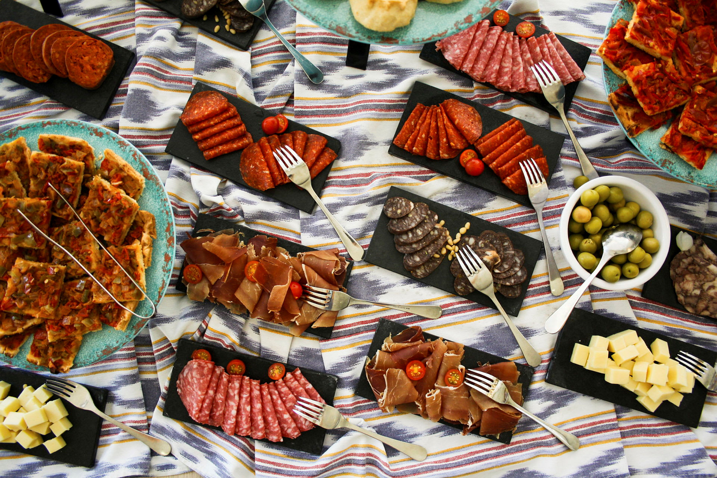 En madudstilling med forskellige tapas inklusive kødprodukter, ost og oliven. (AI-genereret tekst)