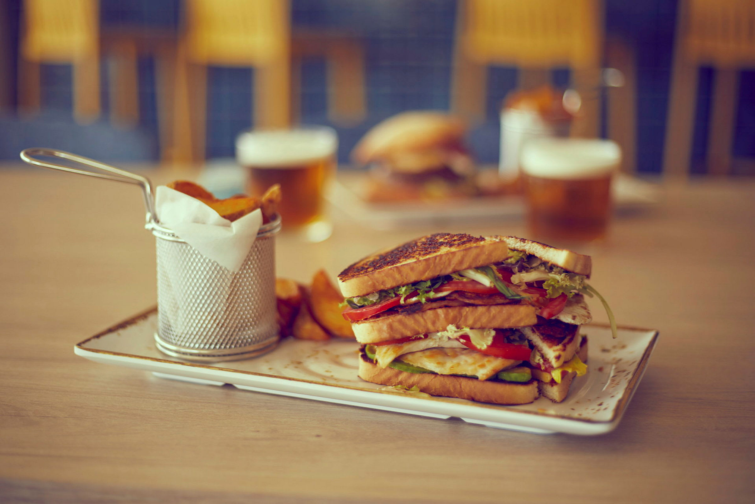 En tallerken med en sandwich og pommes frites ved siden af en drik. (AI-genereret tekst)
