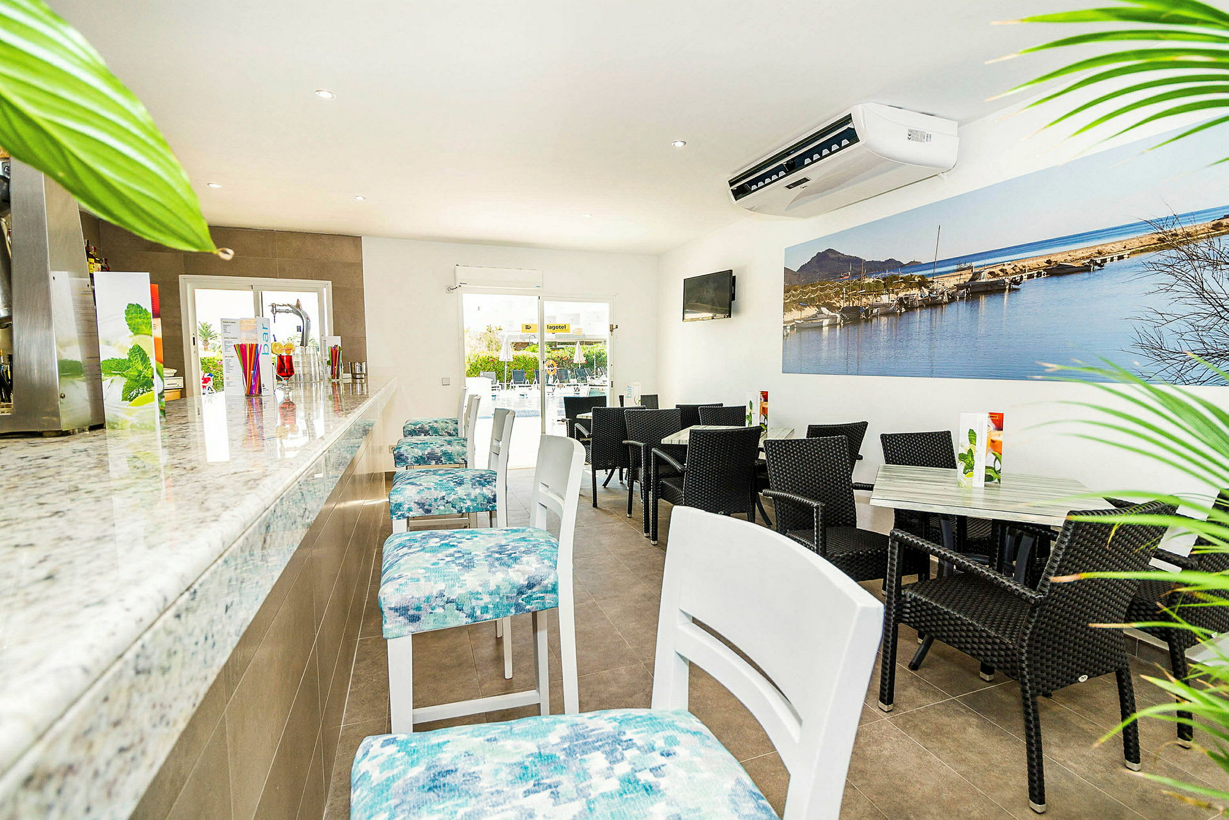 Interiør af en lys og moderne café- eller bardel med en marmorbar og forskellige siddepladser. (AI-genereret tekst)