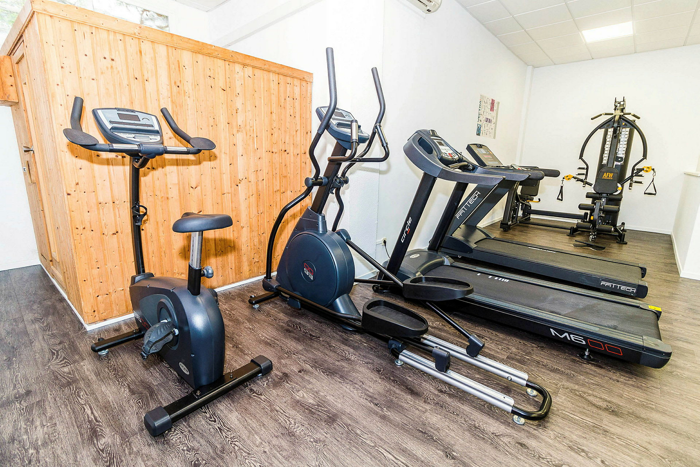 Træningsudstyr inklusive en motionscykel, en crosstrainer og flere løbebånd i et fitnesscenter. (AI-genereret tekst)