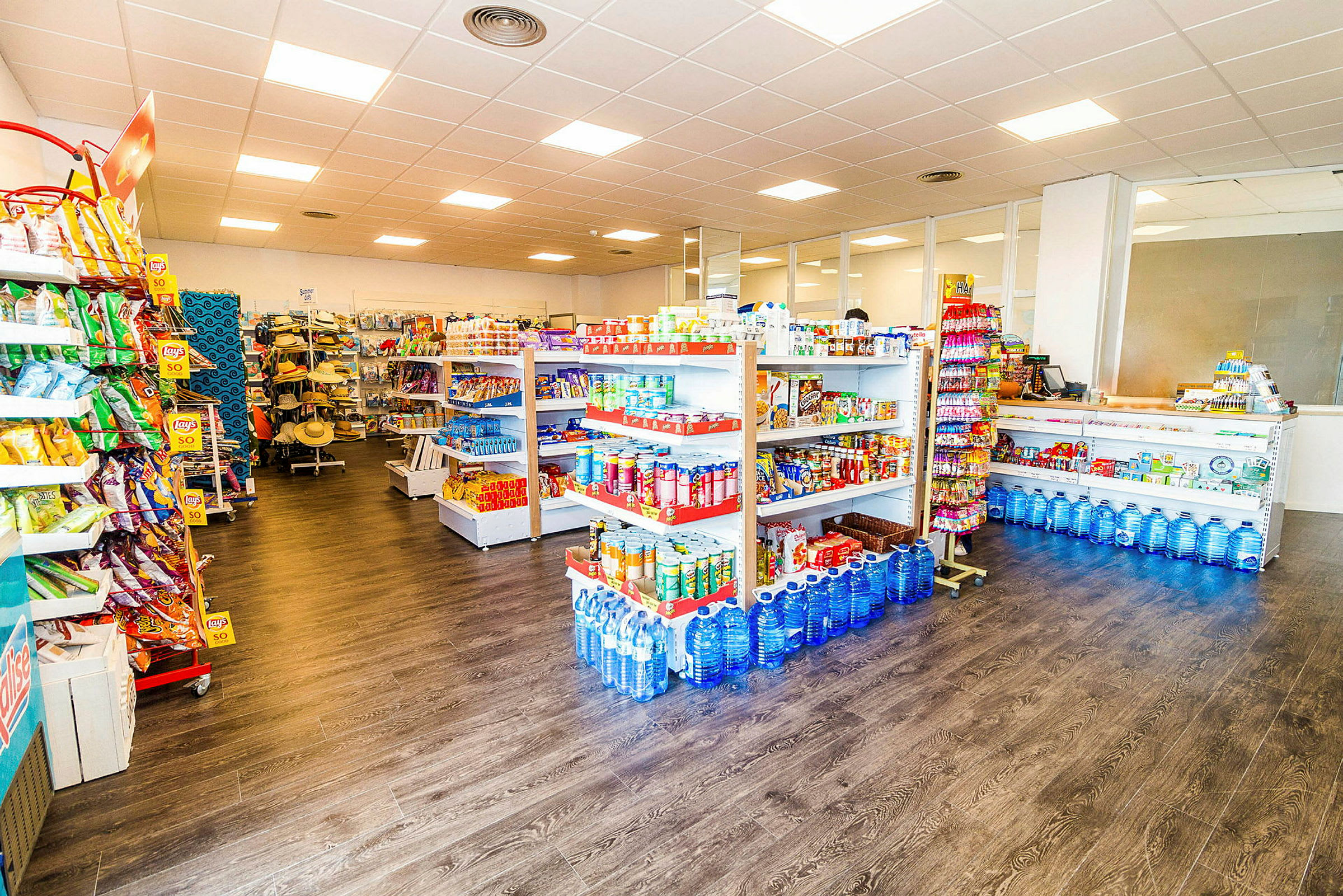 En butik med hylder fyldt med dagligvarer som snacks, vandflasker og andre madvarer. (AI-genereret tekst)